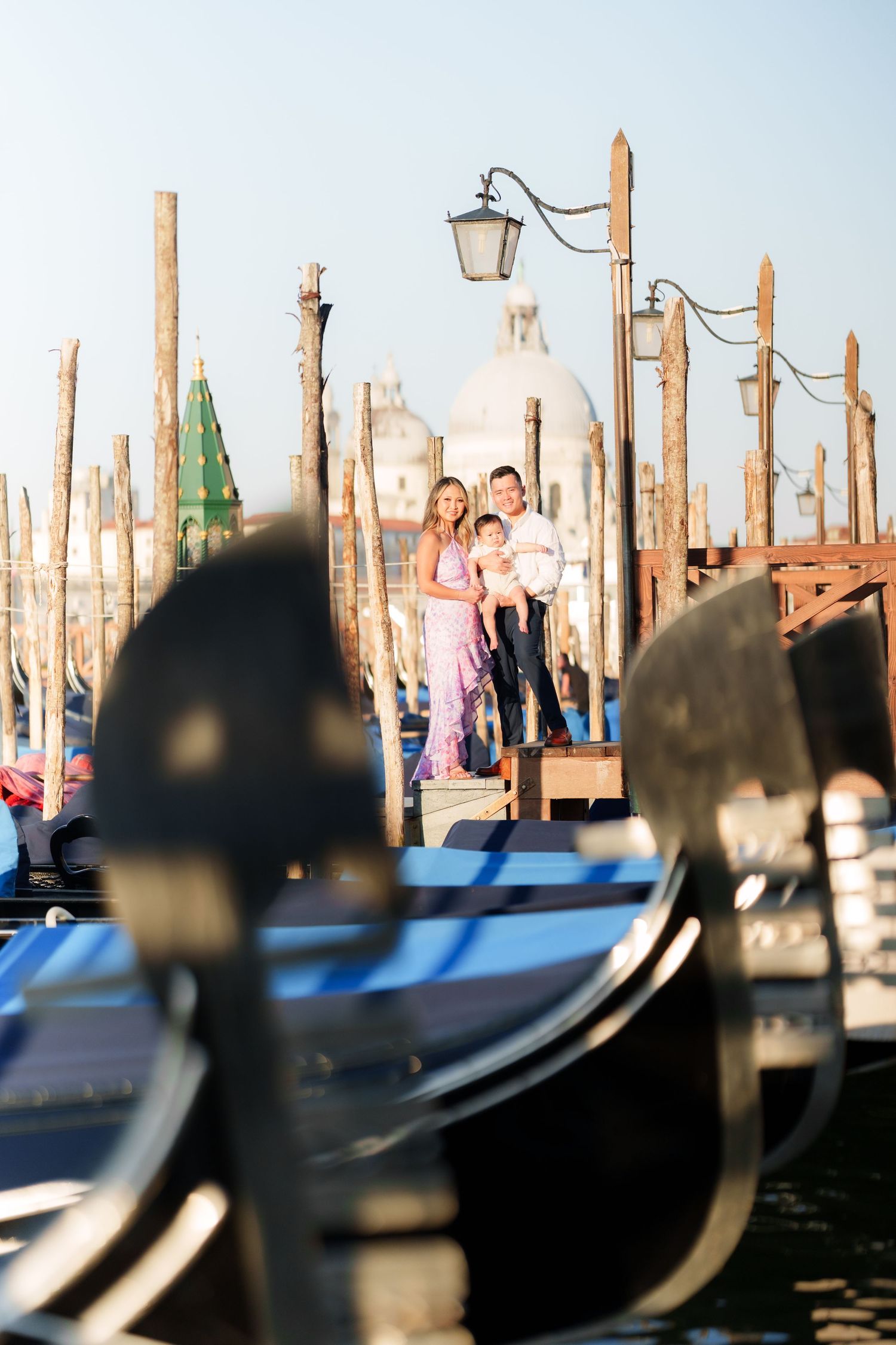 Family posing on Venice gondola dock with Santa Maria della Salute church in background, Italy.