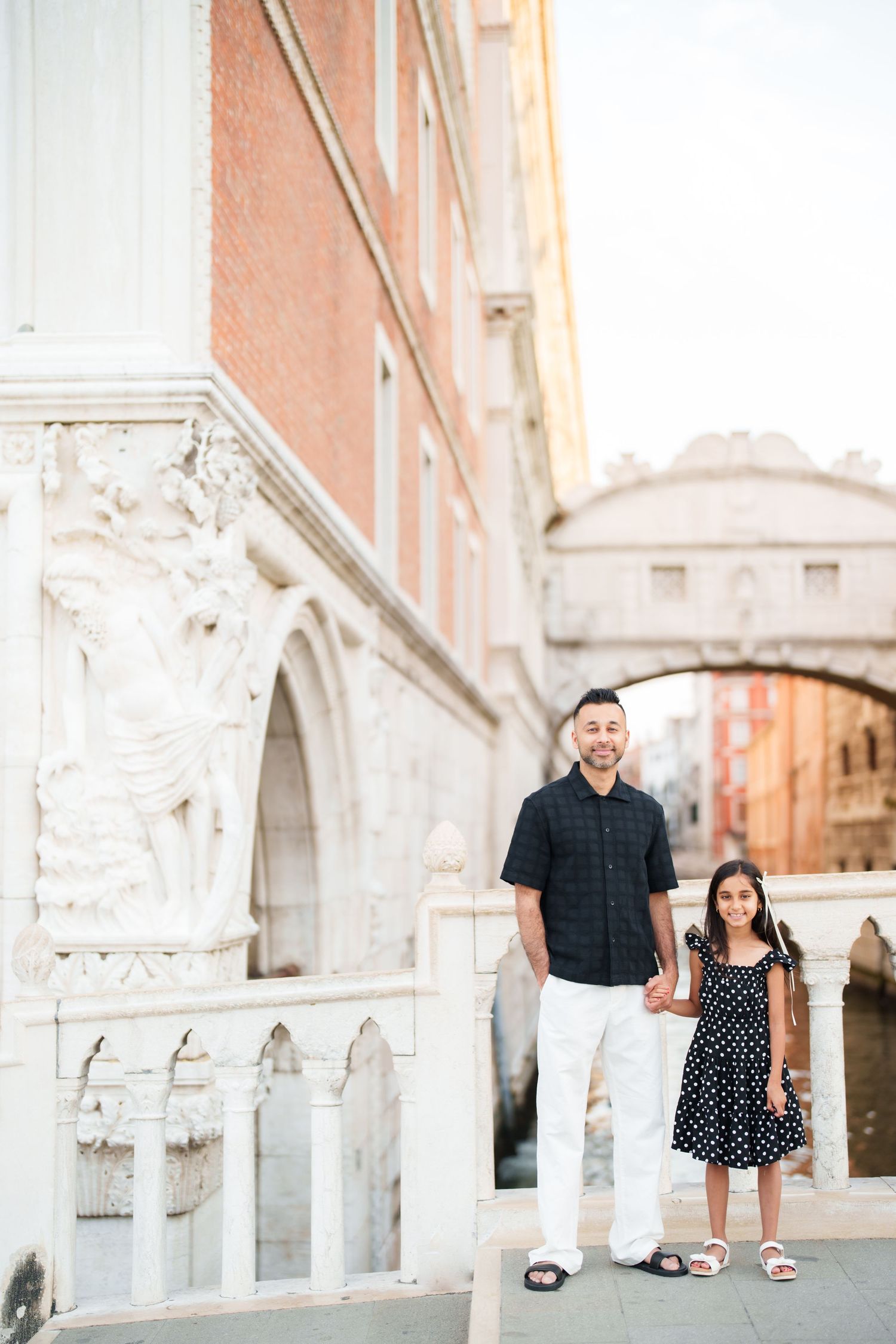 A man and young girl hold hands near the Bridge of Sighs in Venice, Italy.