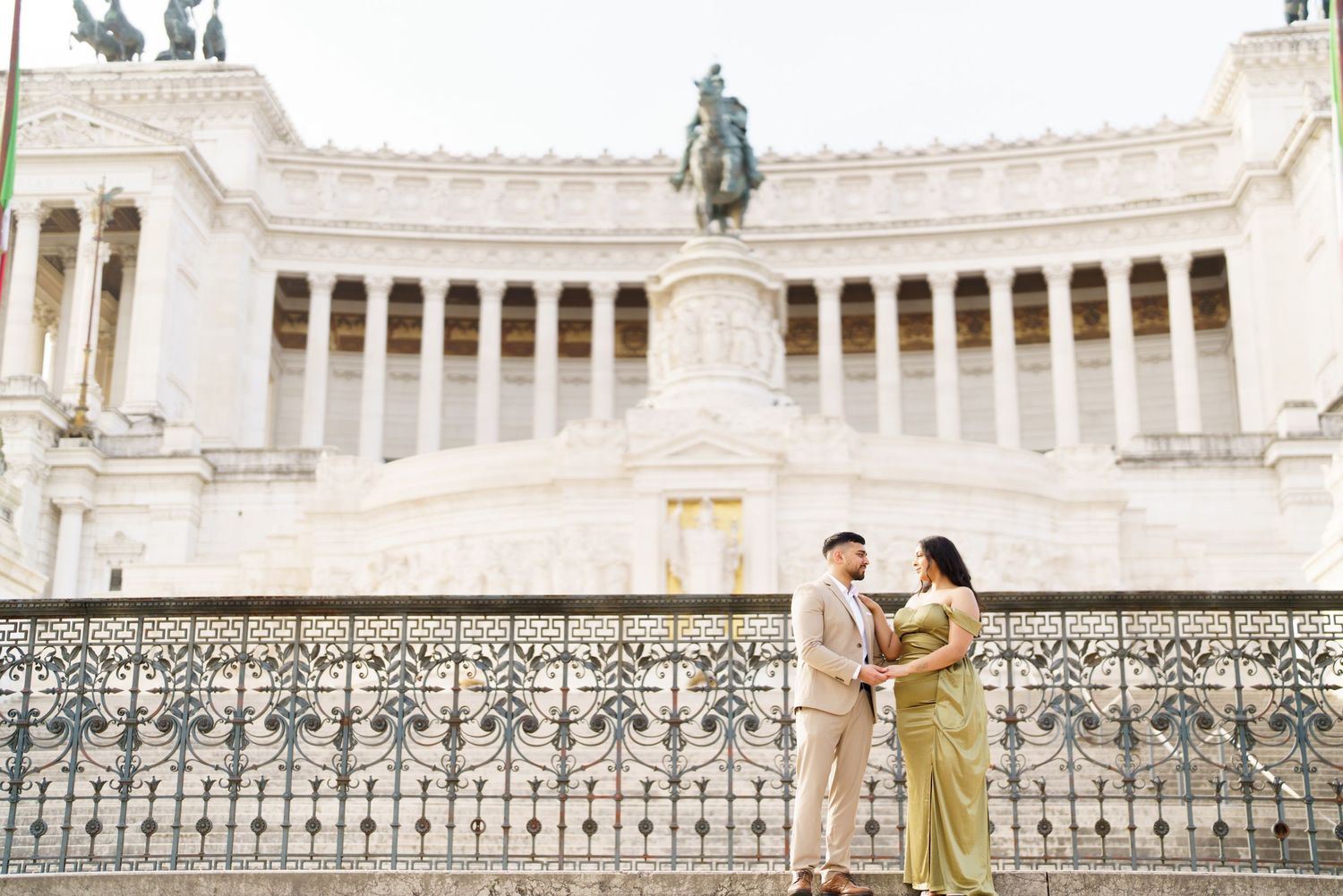 Couple posing romantically in front of the Altare della Patria monument in Rome, Italy.