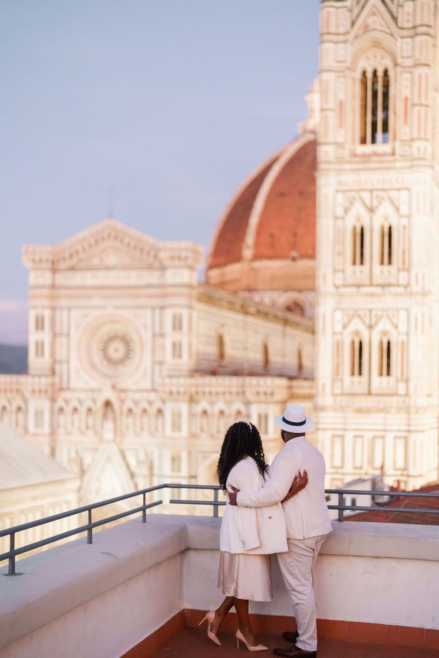 Couple embracing on a rooftop terrace overlooking the Florence Cathedral at dusk in Italy.