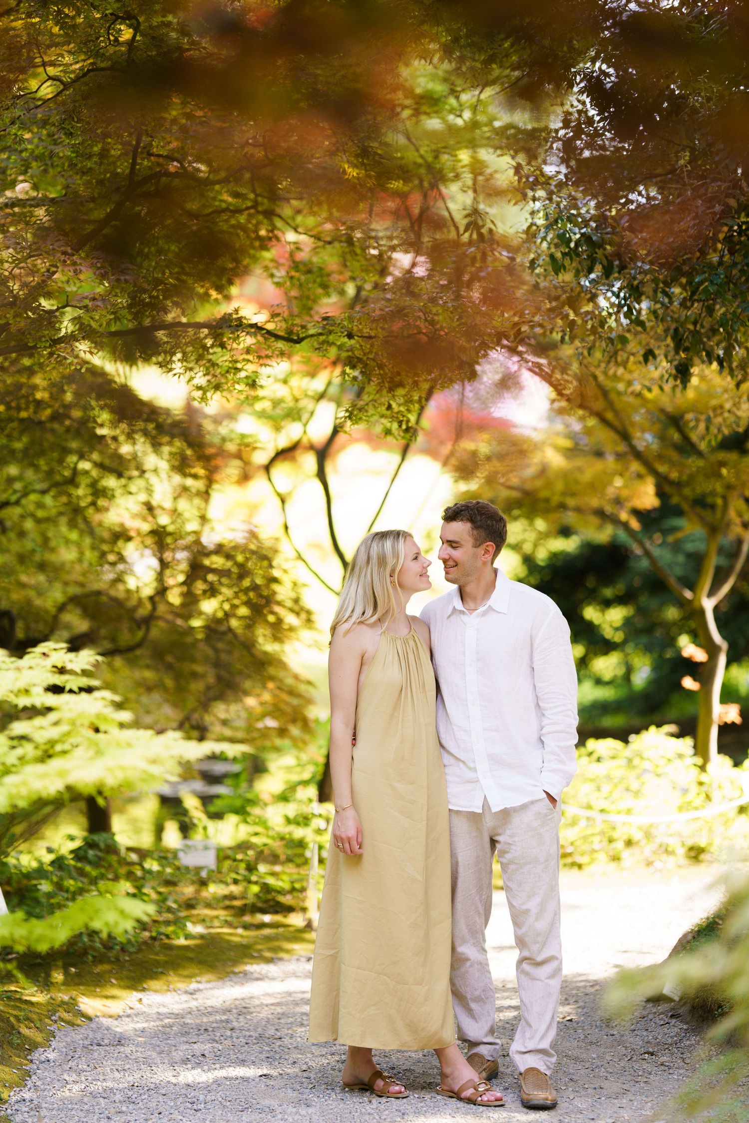 Couple walking hand in hand through a colorful autumn Japanese garden with vibrant red and green maple trees.