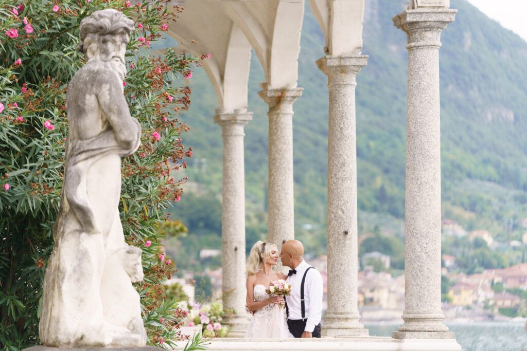 Scenic colonnade with stone pillars and flowering plants at Villa del Balbianello.