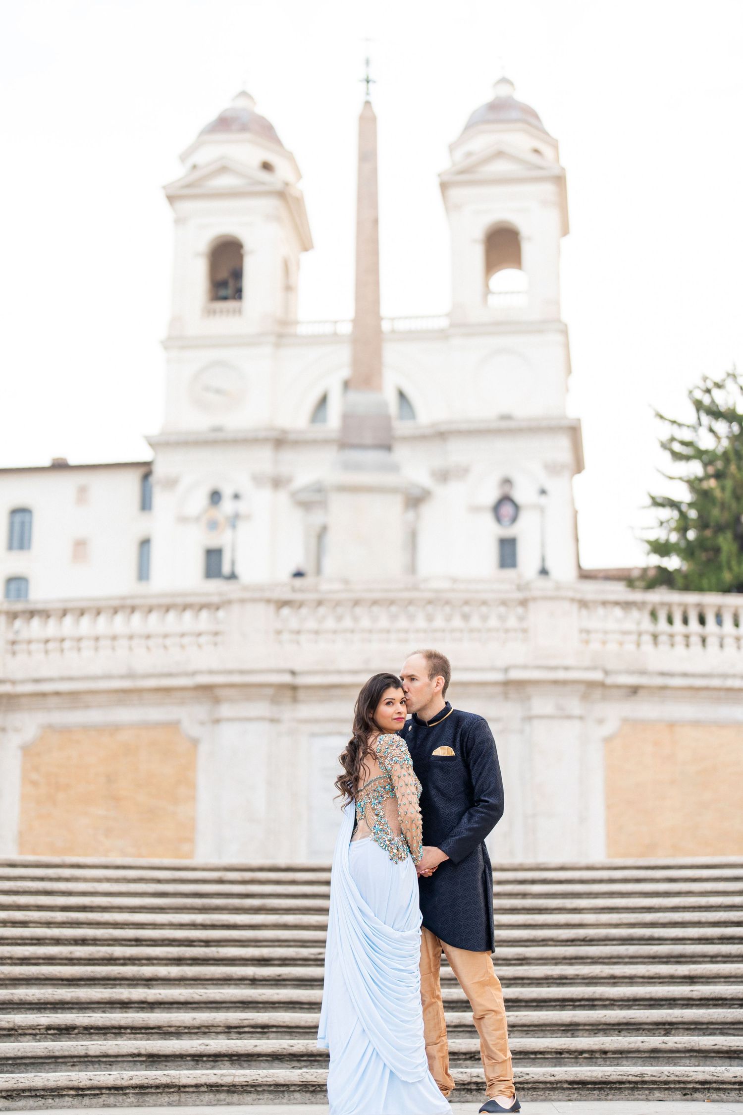 Romantic couple on Spanish Steps with the Church of Trinità dei Monti in background.