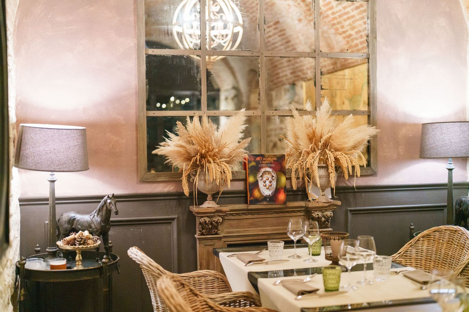Upscale dining room with rattan chairs, dried palm arrangements and chandelier lighting.