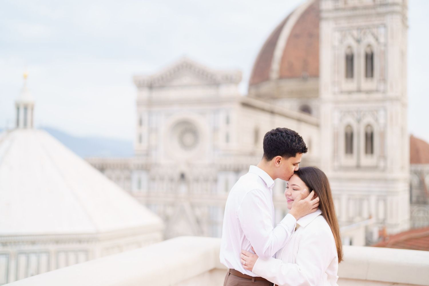 Couple sharing intimate moment on rooftop with Florence Cathedral view.