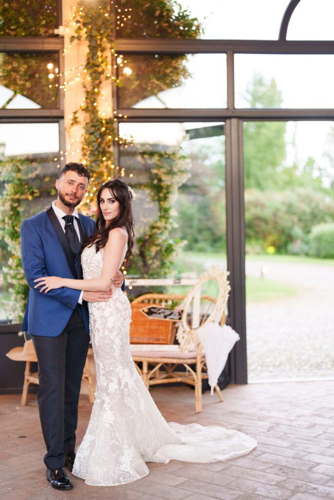 Wedding couple dancing in elegant venue with string lights and greenery decor.