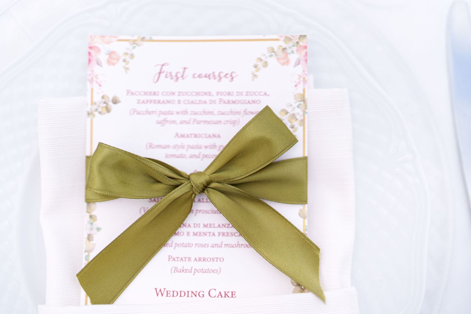 Wedding invitation details featuring olive green ribbon bows on white paper.