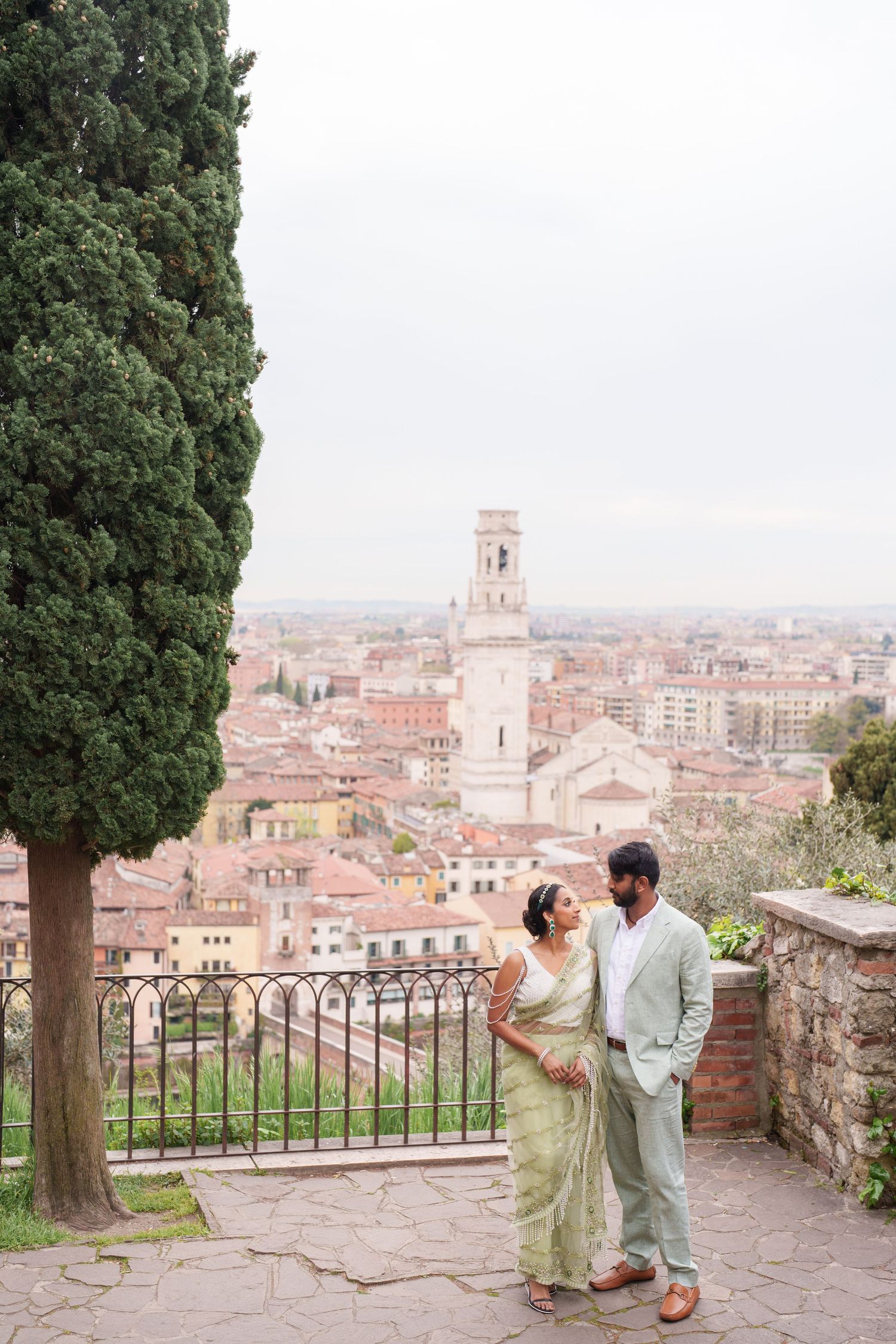 Couple enjoying a romantic moment on a scenic overlook with views of an Italian cityscape and historic architecture below.