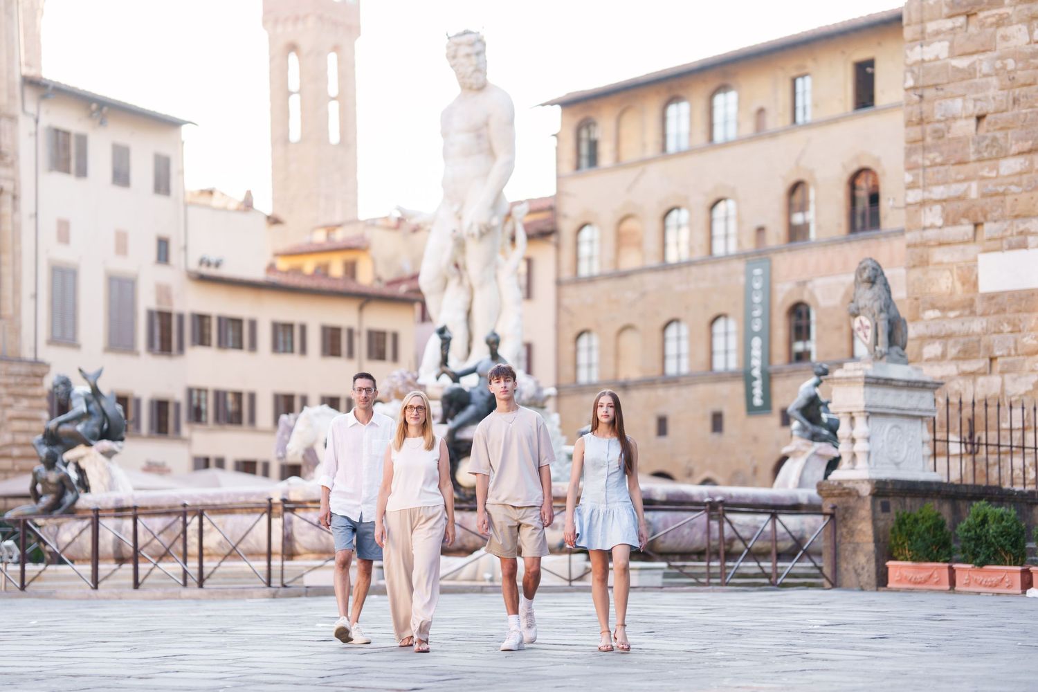 Tourists walking through historic Piazza della Signoria in Florence, Italy with Renaissance architecture in background.