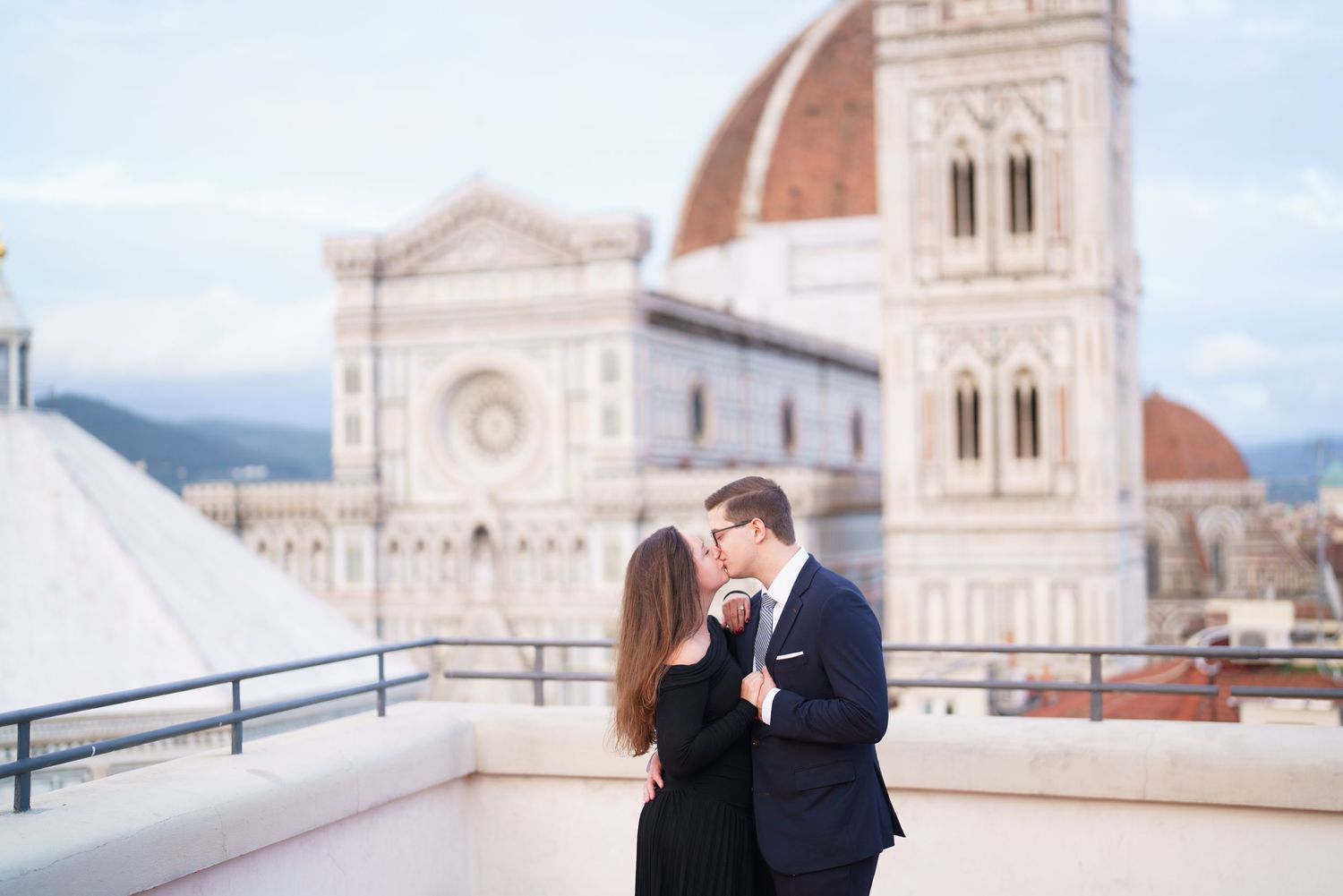 Romantic couple embraces on a terrace overlooking the historic Florence Cathedral and Duomo in Italy.