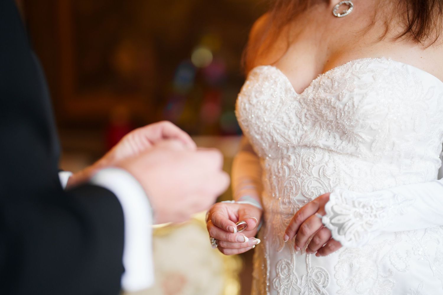 A close-up shot of hands exchanging wedding rings during a traditional ceremony.