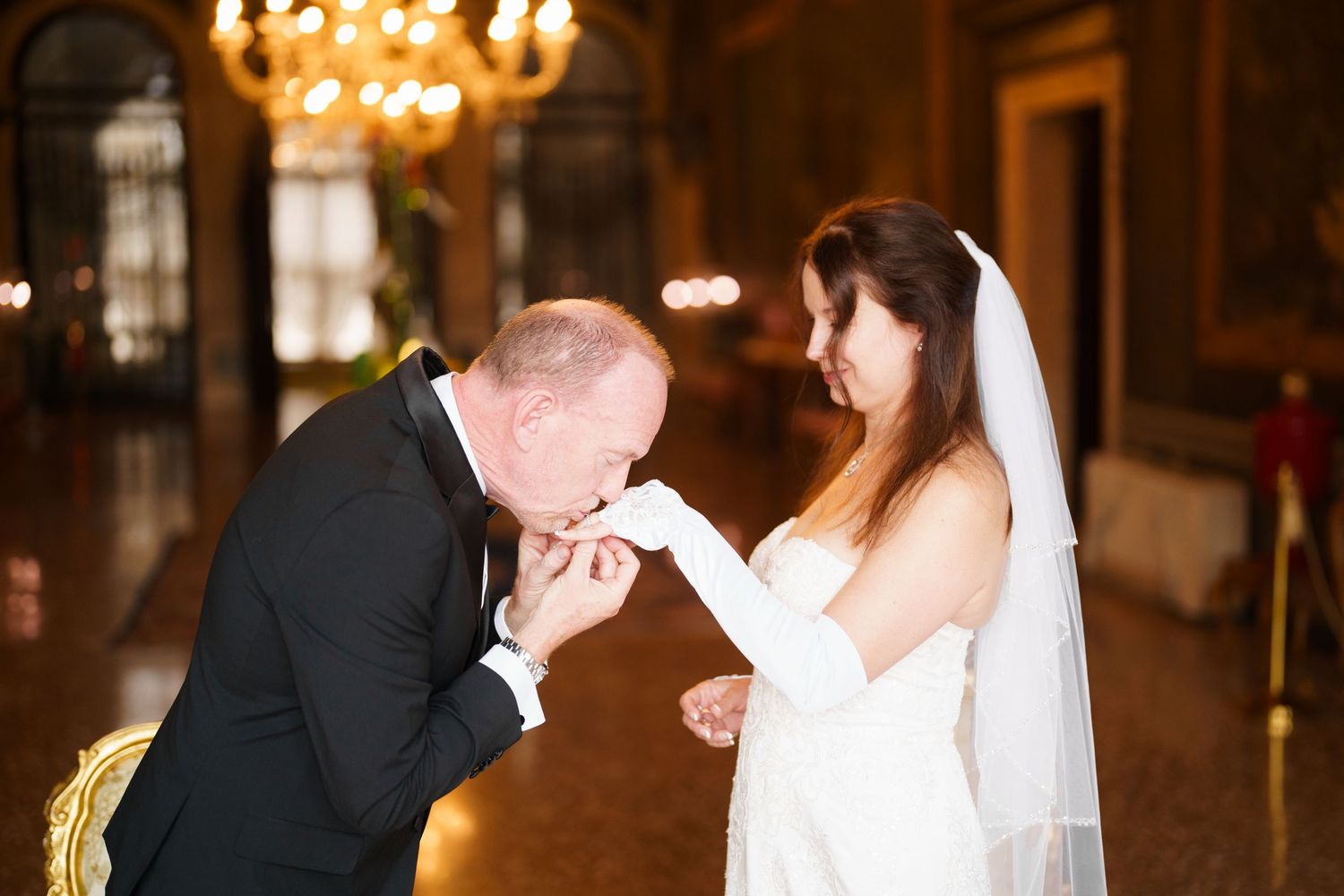 A couple shares a romantic moment during their wedding reception in an elegantly lit ballroom.