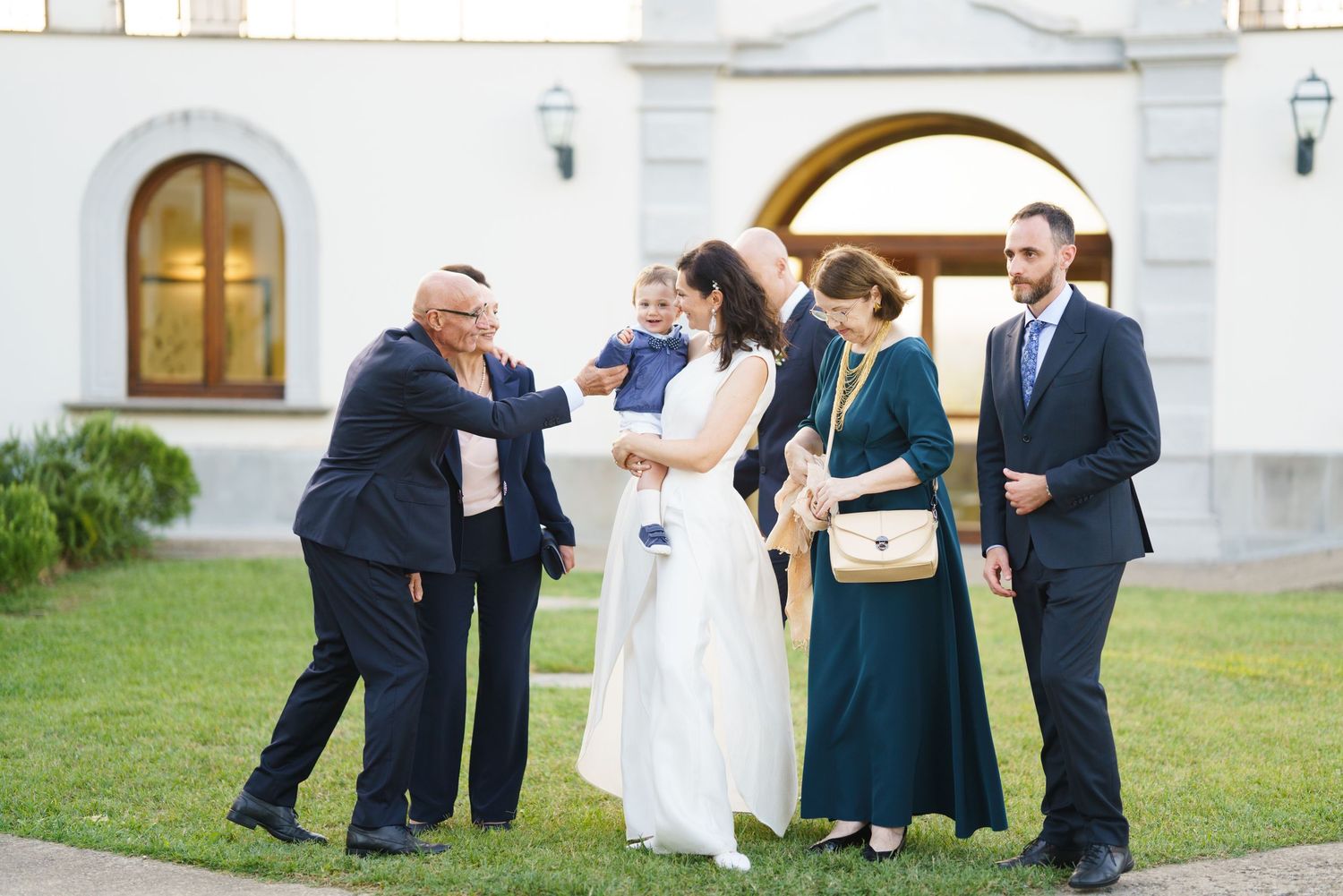 Wedding party members sharing joyful moments on church lawn during photo session.