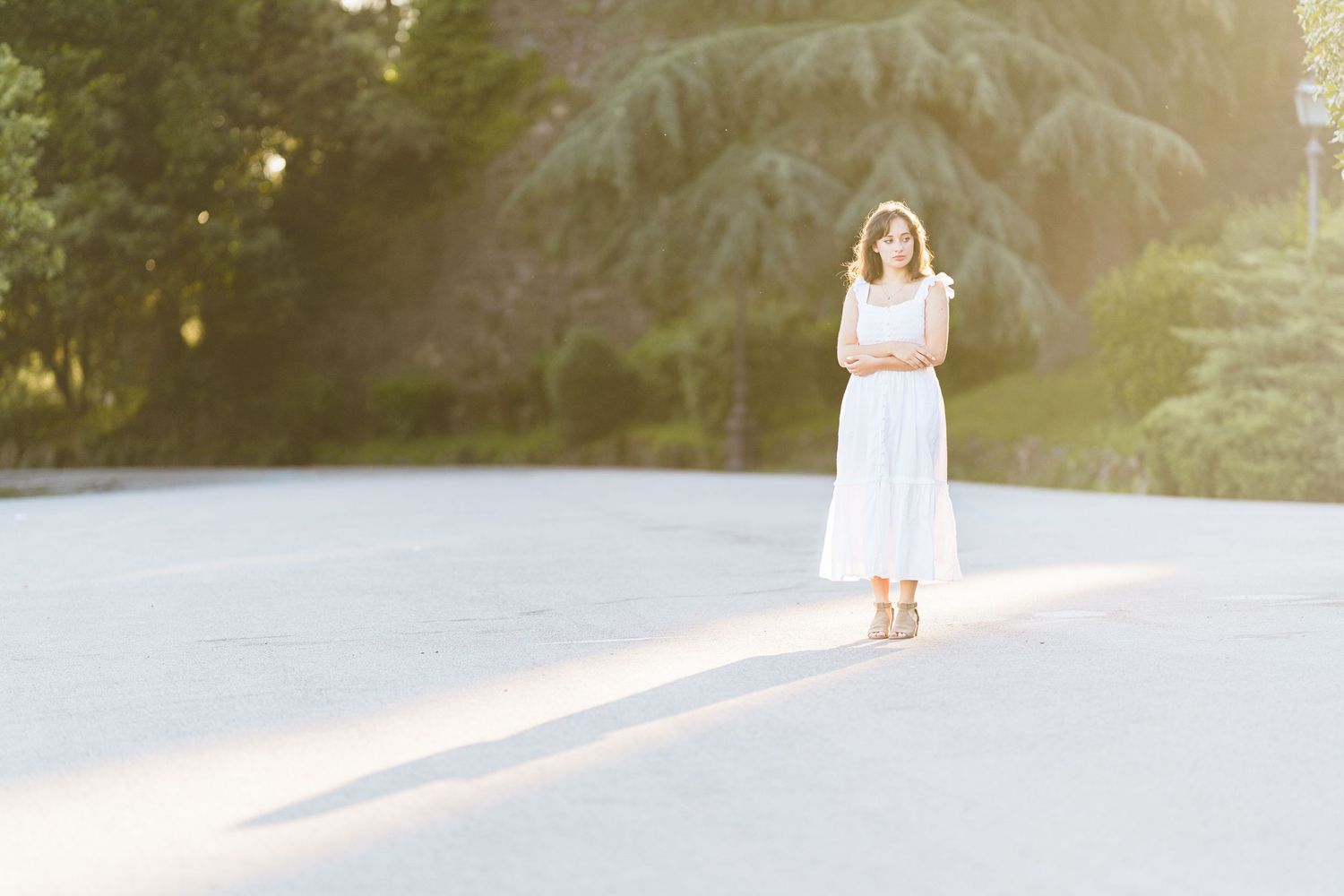 A person in a white dress walks down a misty road at sunset creating a dreamy ethereal scene.