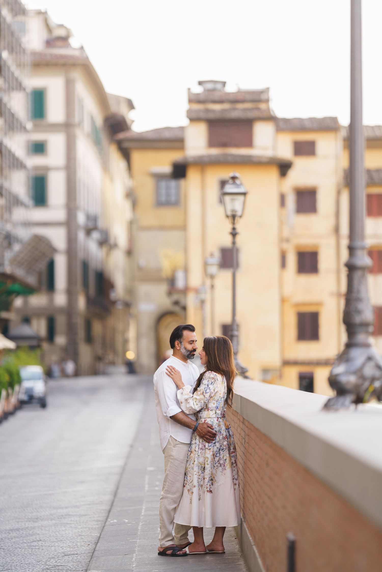 Romantic couple embracing on a cobblestone street in Florence, Italy, surrounded by classic Italian architecture.