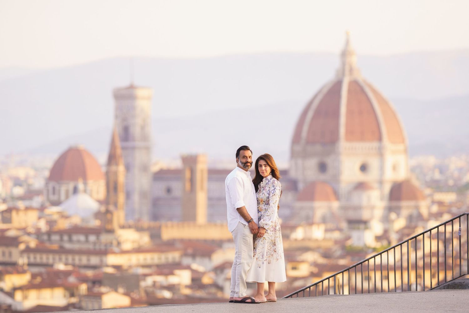 Couple holding hands in Florence Italy with the iconic Duomo cathedral and city skyline at golden hour.