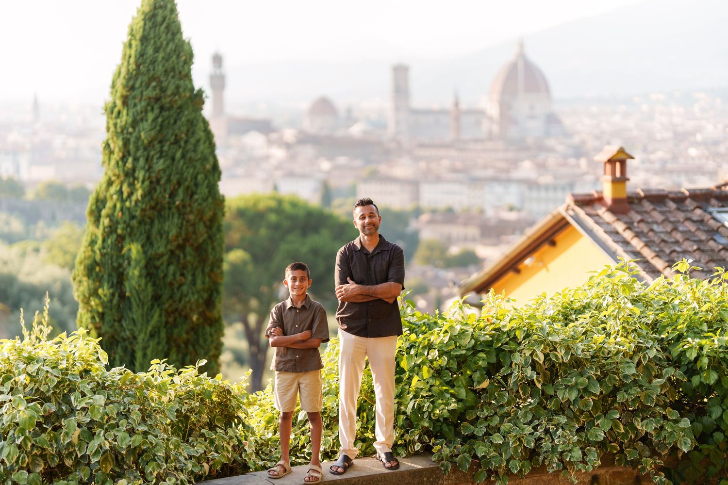 Man and boy posing on a terrace overlooking Florence skyline with the Duomo cathedral visible in background.