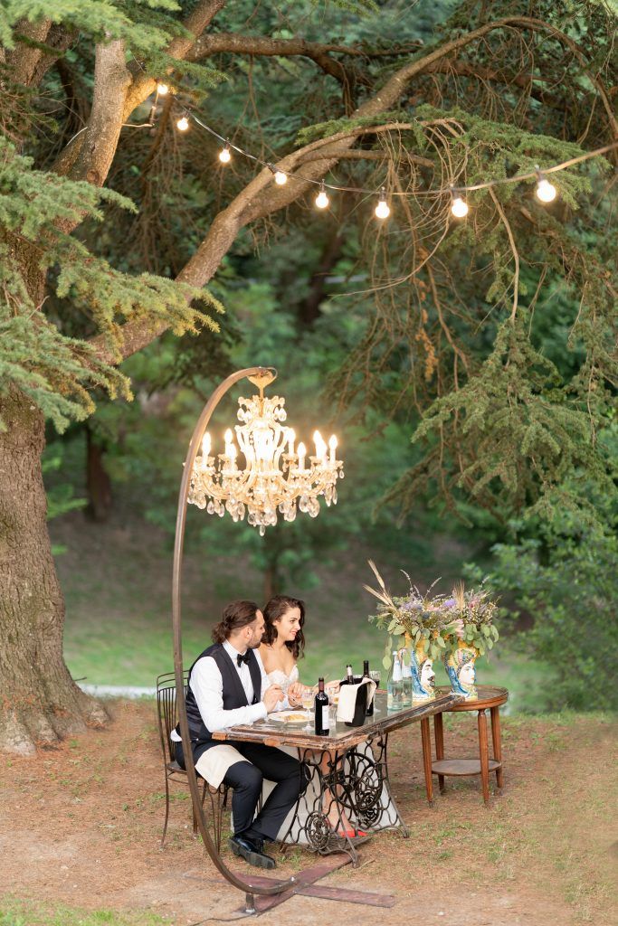 Outdoor garden setting with string lights and crystal chandeliers creating a romantic atmosphere.