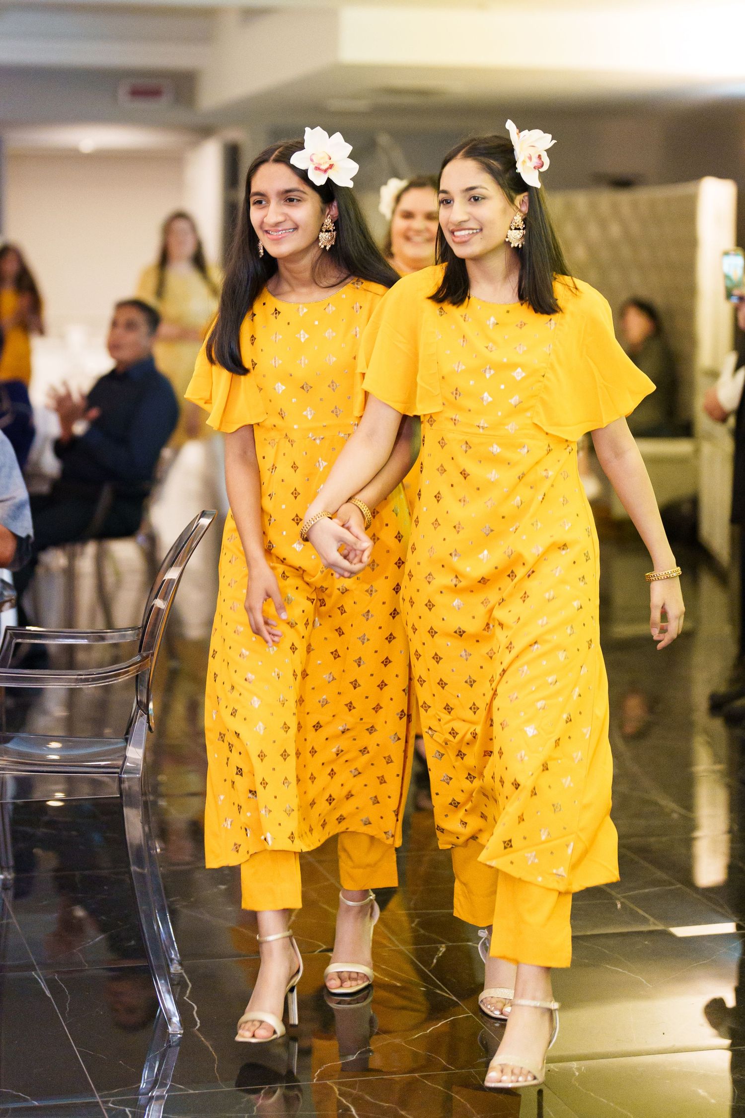 People wearing coordinated yellow patterned outfits walking together at an indoor venue.