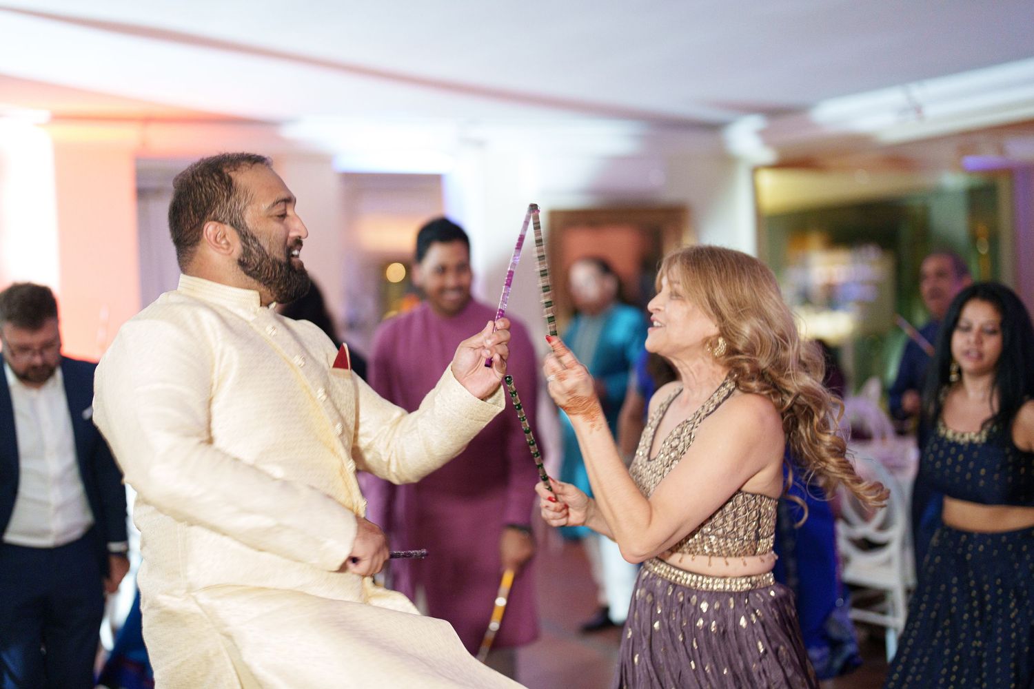 Two guests dancing and celebrating with sparklers at an indoor party.