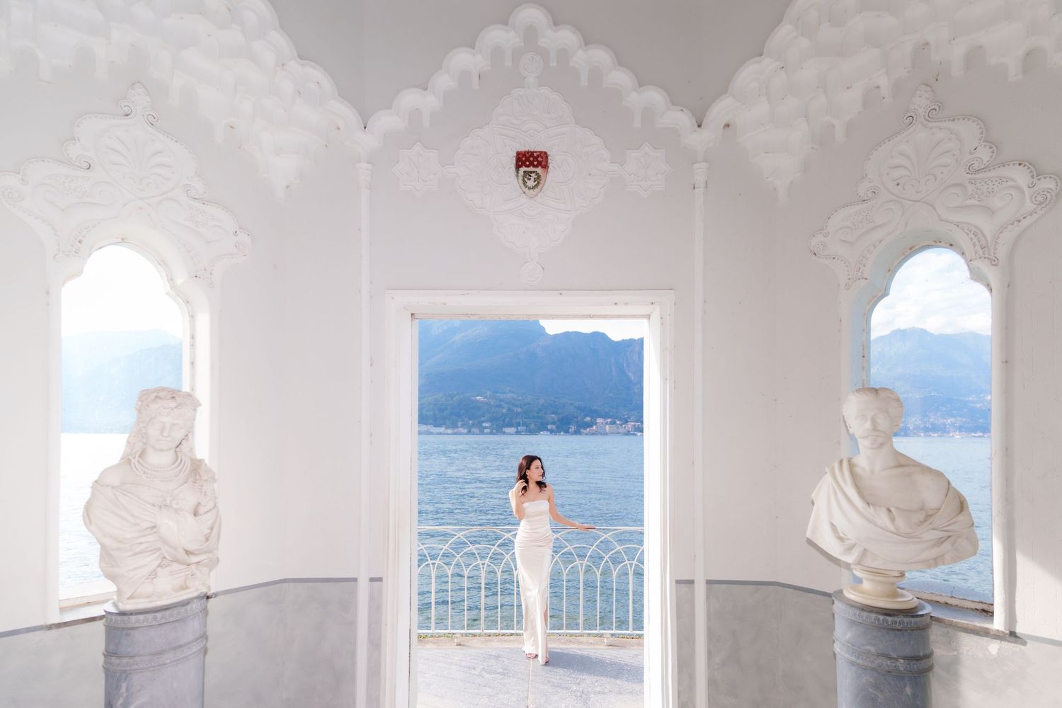 White arched Mediterranean architecture frames scenic coastal views along a seaside terrace walkway.