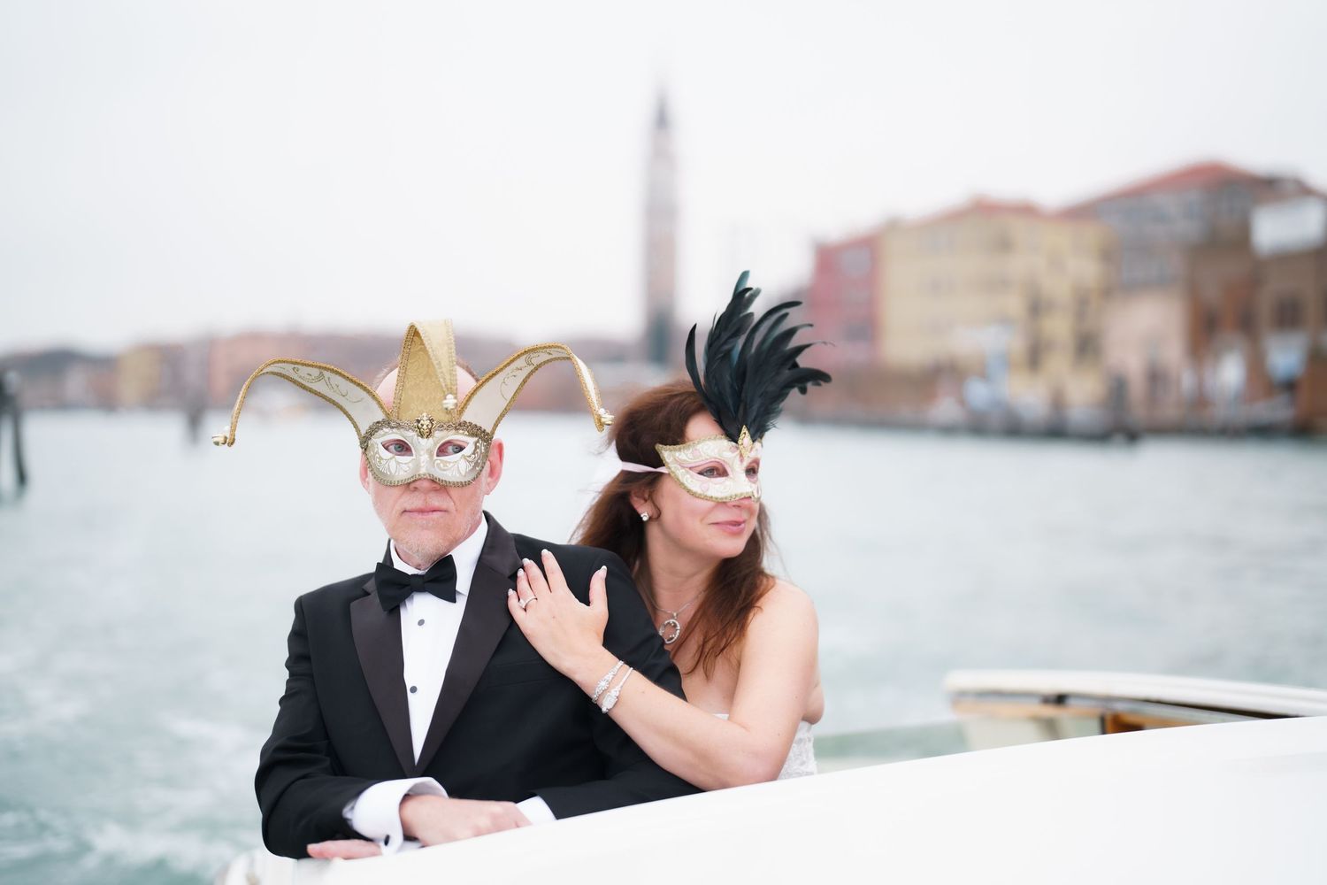 A couple in formal attire poses along a waterfront during a romantic winter photo session.