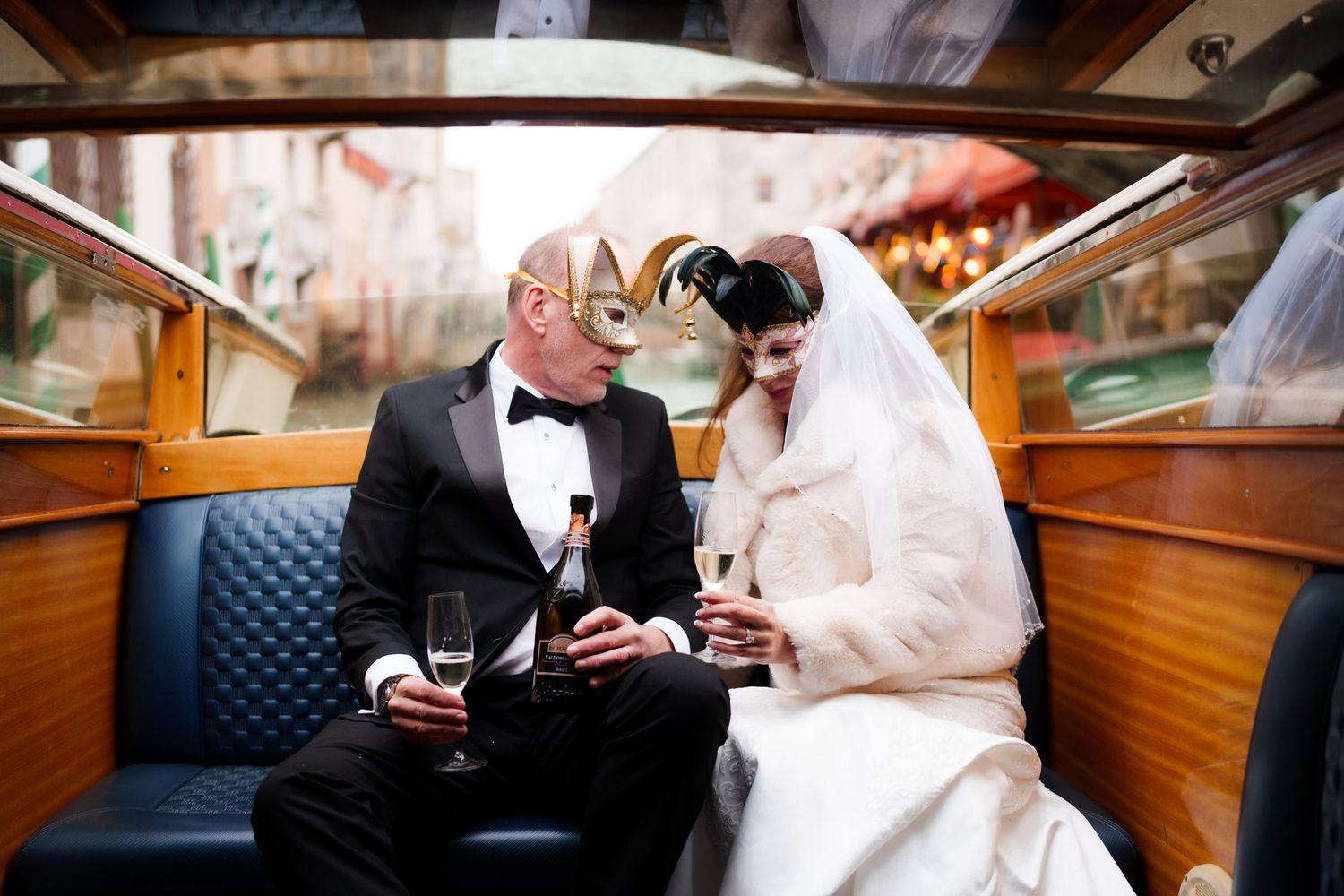 Elegant couple in formal wedding attire share intimate moments while seated in vintage train car interior.