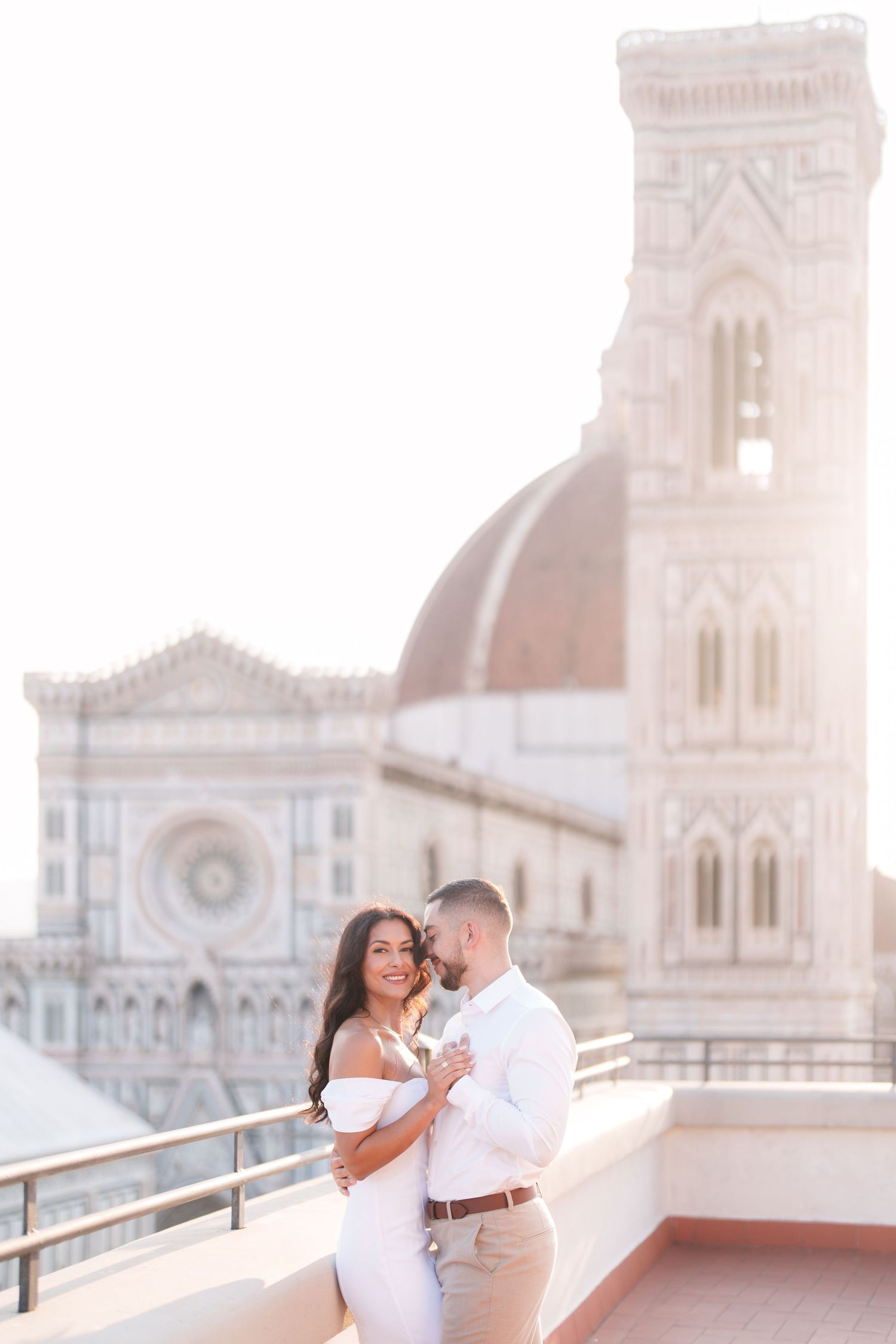 A romantic couple embraces in front of Florence Cathedral during golden hour in Italy.