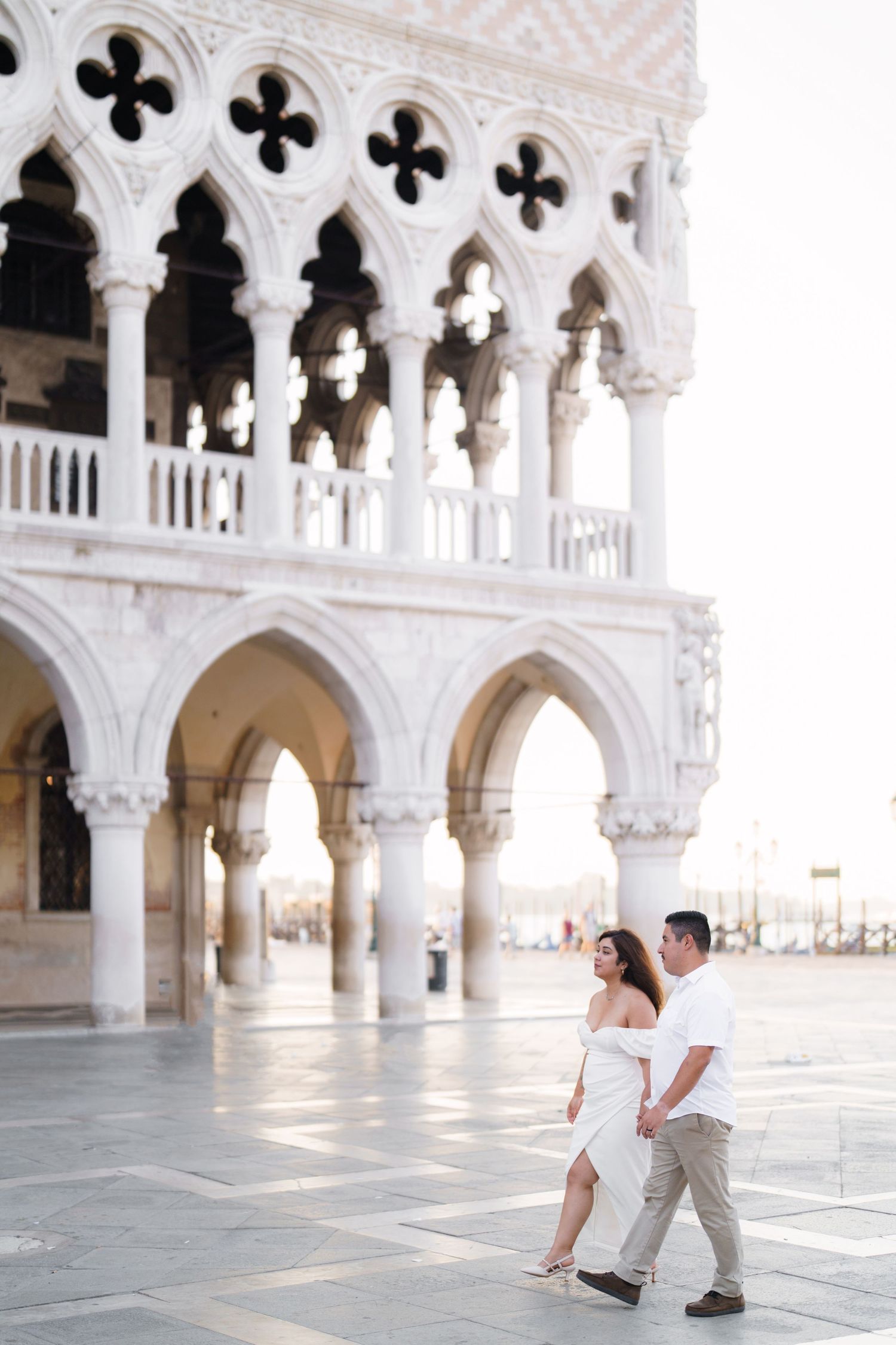 A couple shares a romantic moment in the ornate architecture of Venice's Doge's Palace courtyard.
