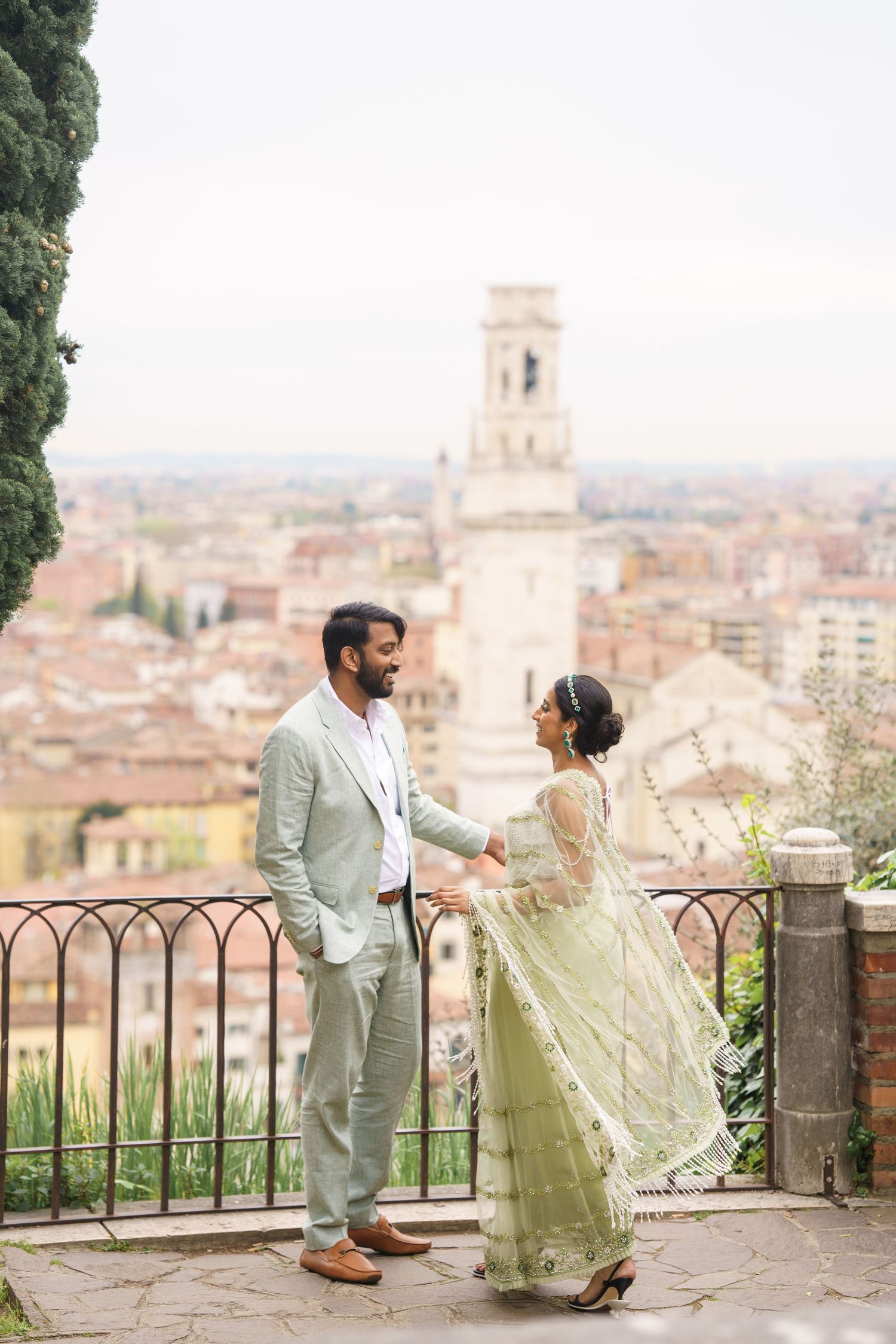 A couple shares a romantic moment overlooking a scenic Italian cityscape with historic architecture and bell towers.
