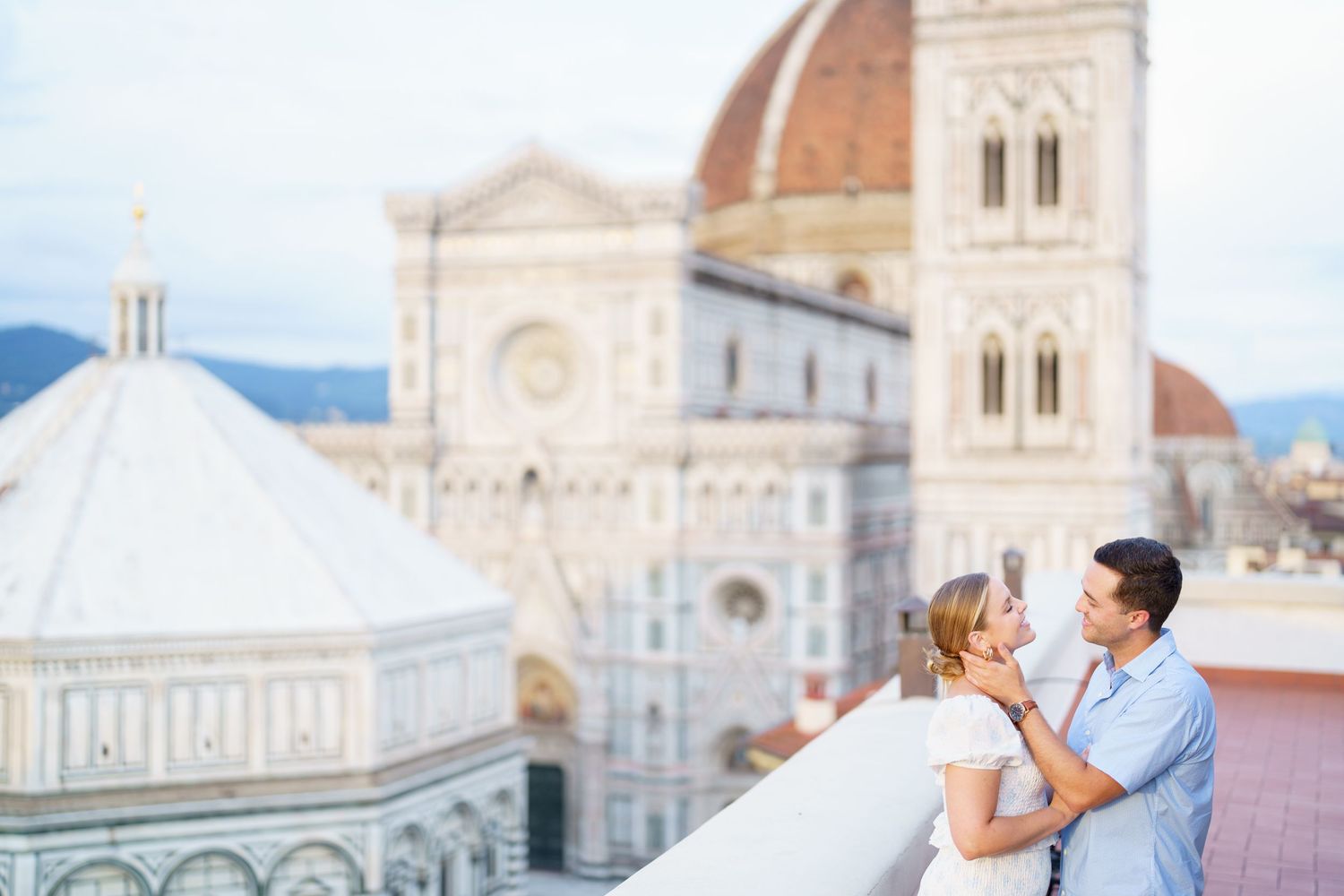 A romantic couple embraces in front of the iconic Florence Cathedral and Duomo in Italy during sunset.