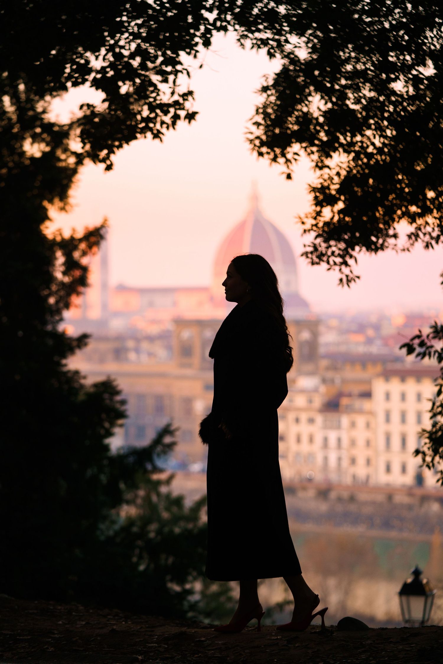 A series of silhouettes against a sunset cityscape in Florence, Italy shows romantic figures walking along a path.