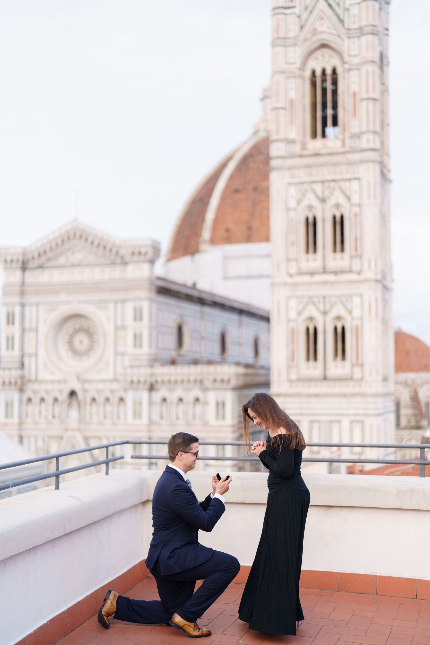A romantic proposal scene unfolds on a rooftop terrace overlooking the historic Duomo cathedral in Florence, Italy.