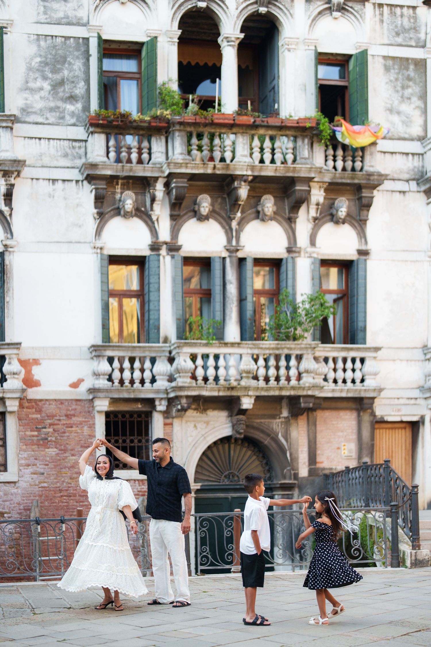 Family of four enjoying a sunny day in Venice, Italy, posing in front of an ornate historic building.