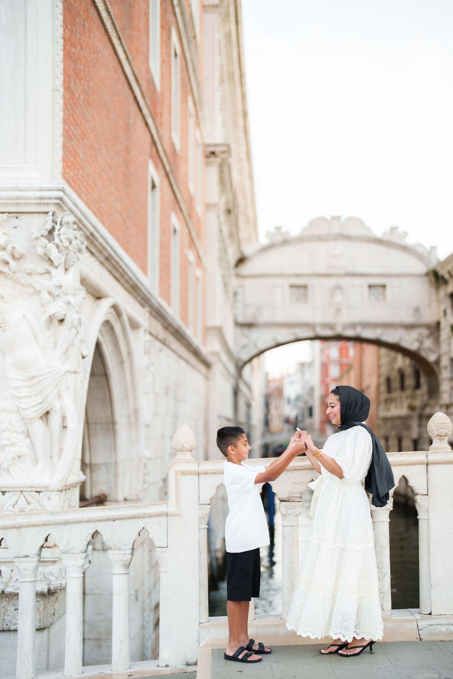 Muslim mother and son holding hands near the Bridge of Sighs in Venice, Italy.