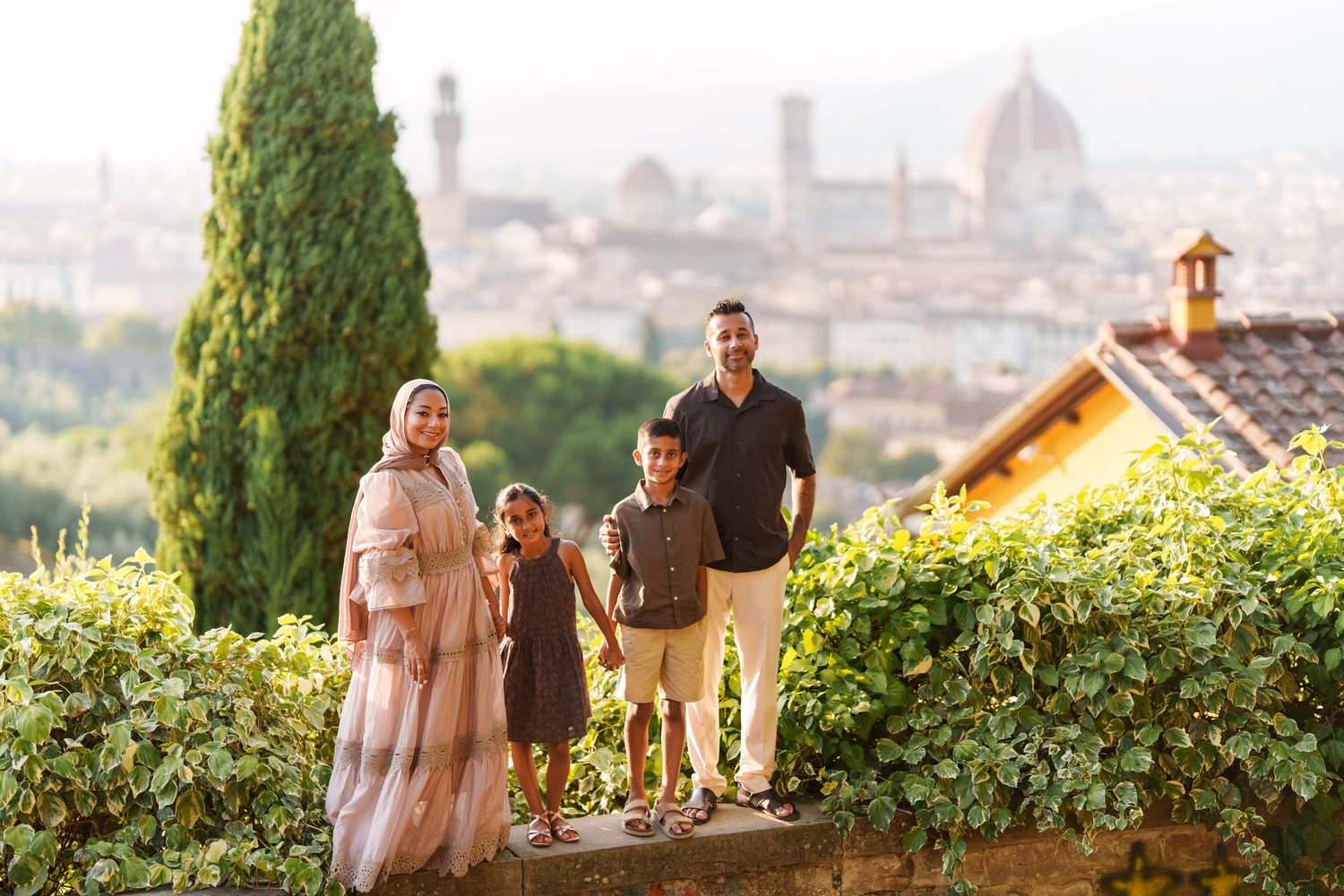 Family of four posing in Florence, Italy, with the iconic Duomo cathedral and cityscape visible in the background.