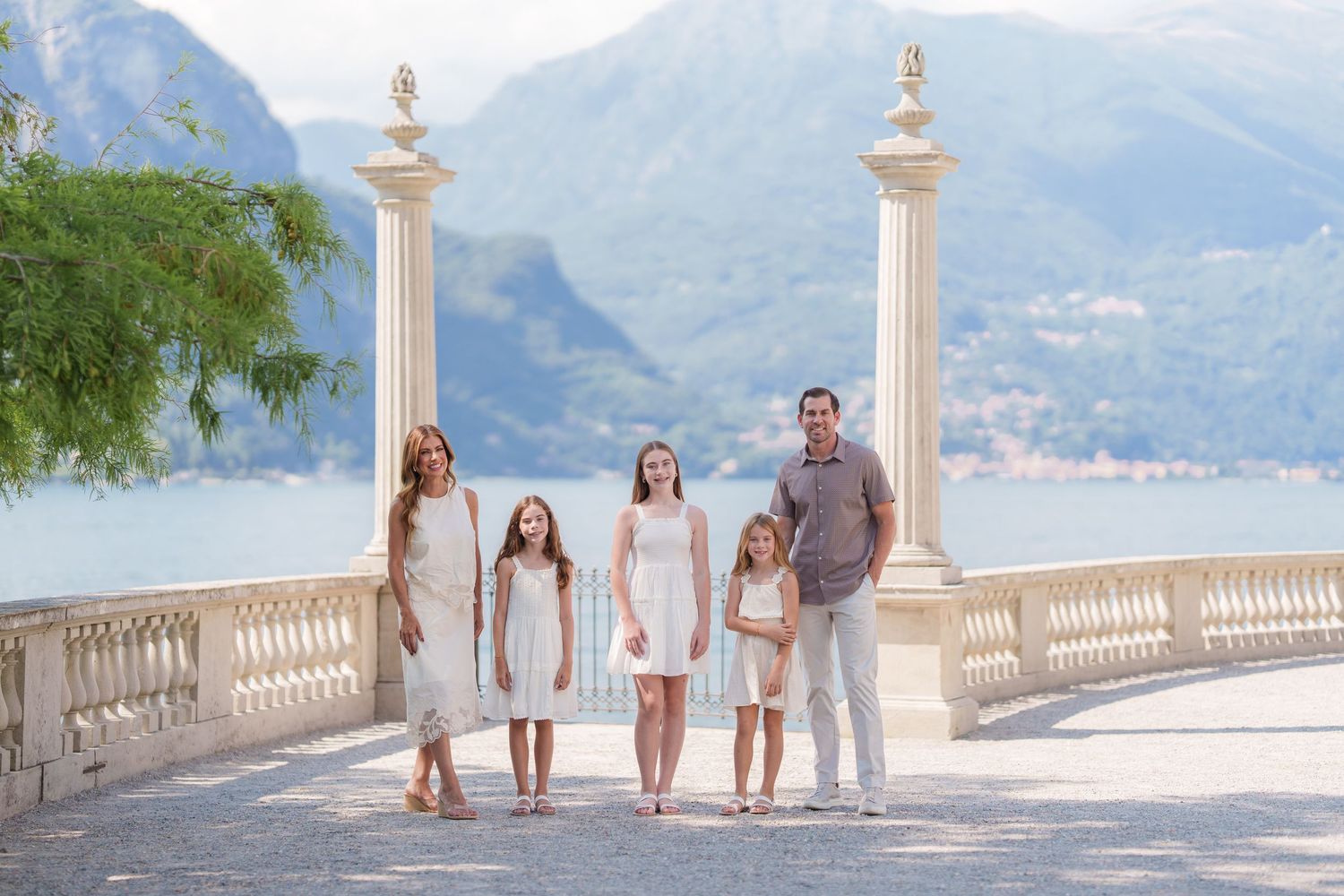 Family of five posing on elegant lakeside terrace with mountain views at Villa Melzi, Lake Como, Italy.