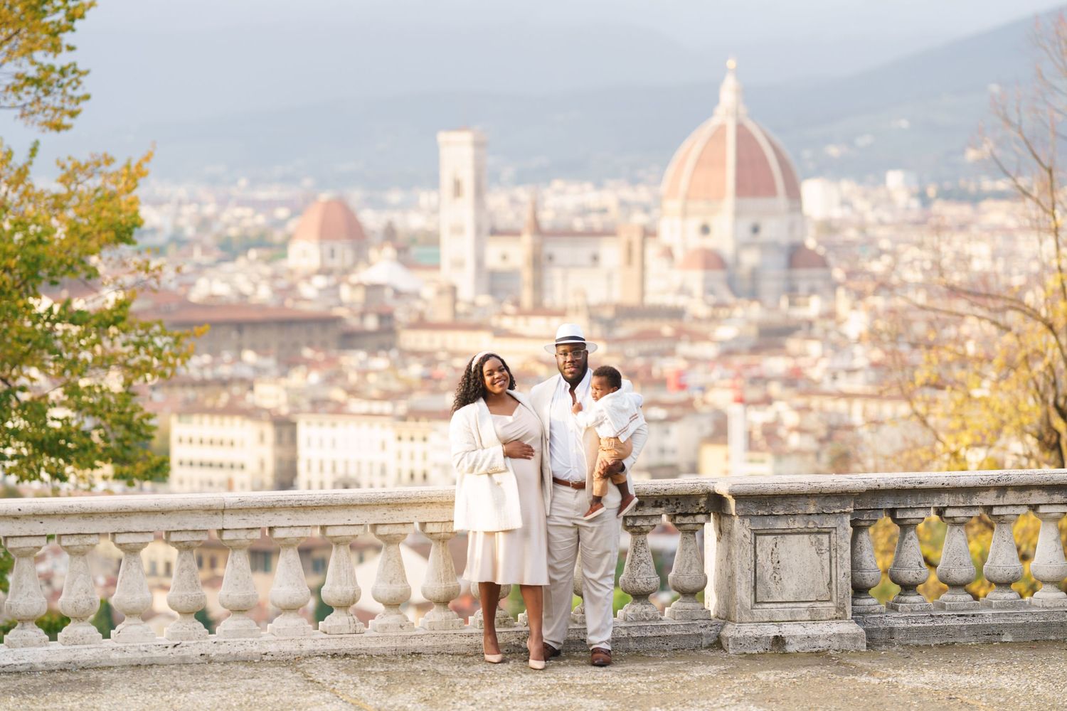 Family posing on a terrace in Florence, Italy, with the iconic Duomo cathedral and city skyline in the background.