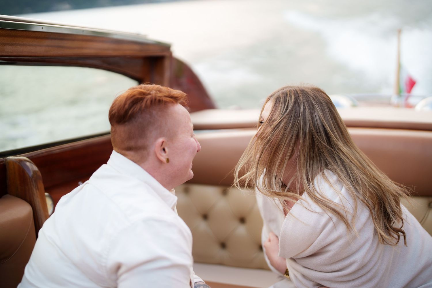Couple sitting together on a luxury wooden boat, sharing an intimate moment on the water.