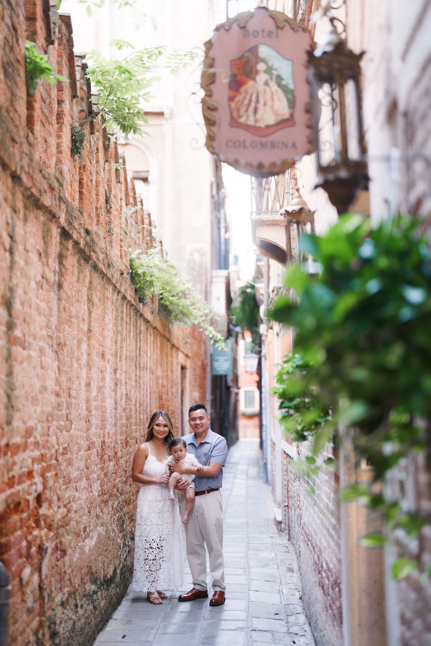 Family posing in a narrow Venice alley near Hotel Colombina, surrounded by brick walls and lush greenery.