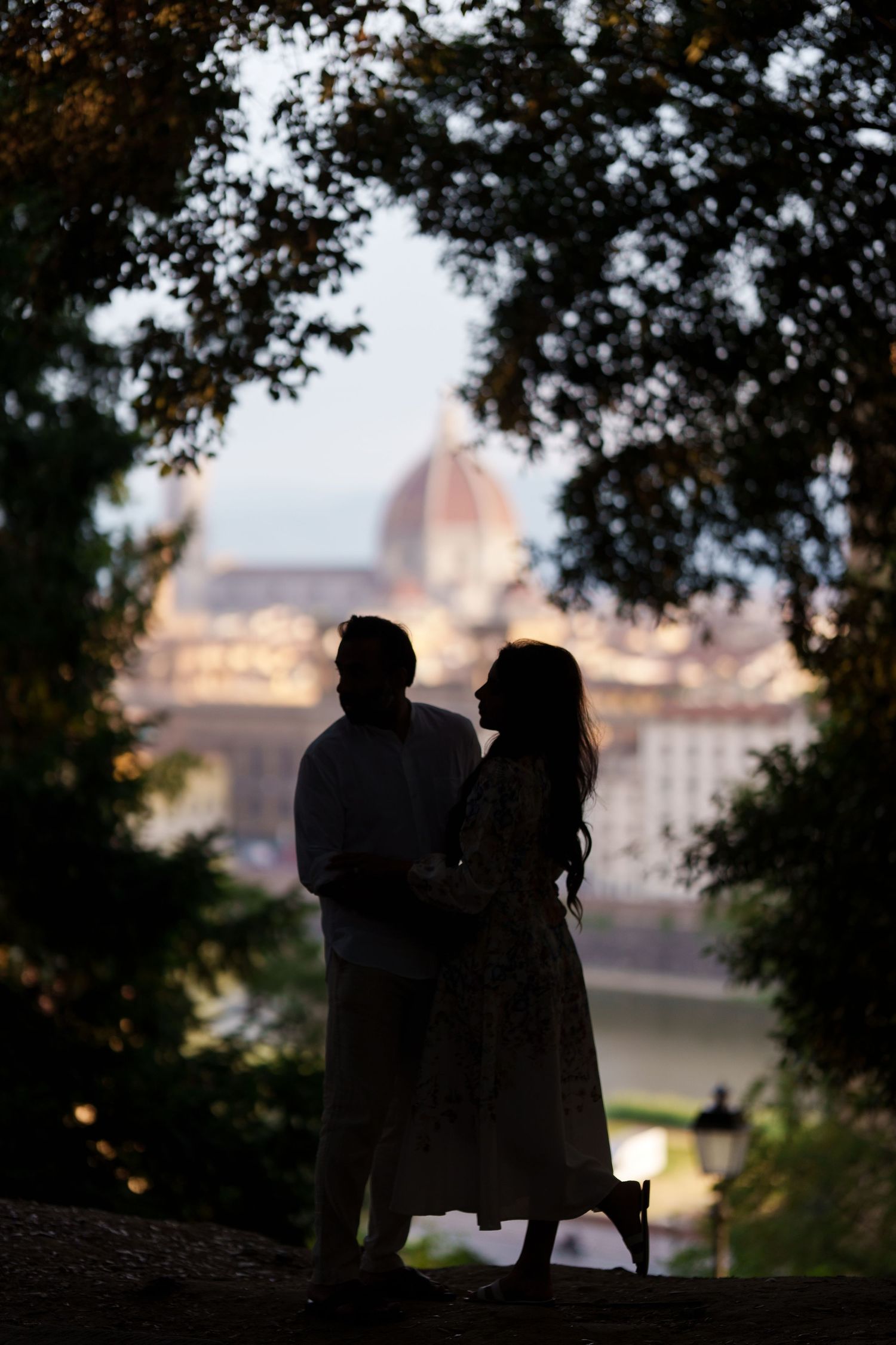 Romantic silhouette of a couple embracing at dusk with Florence Cathedral dome glowing in the background.