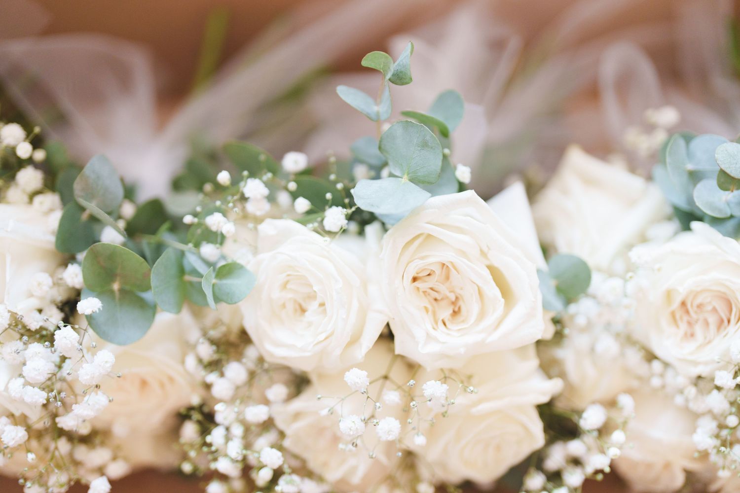 Close-up of white roses and delicate baby's breath in wedding floral arrangement.