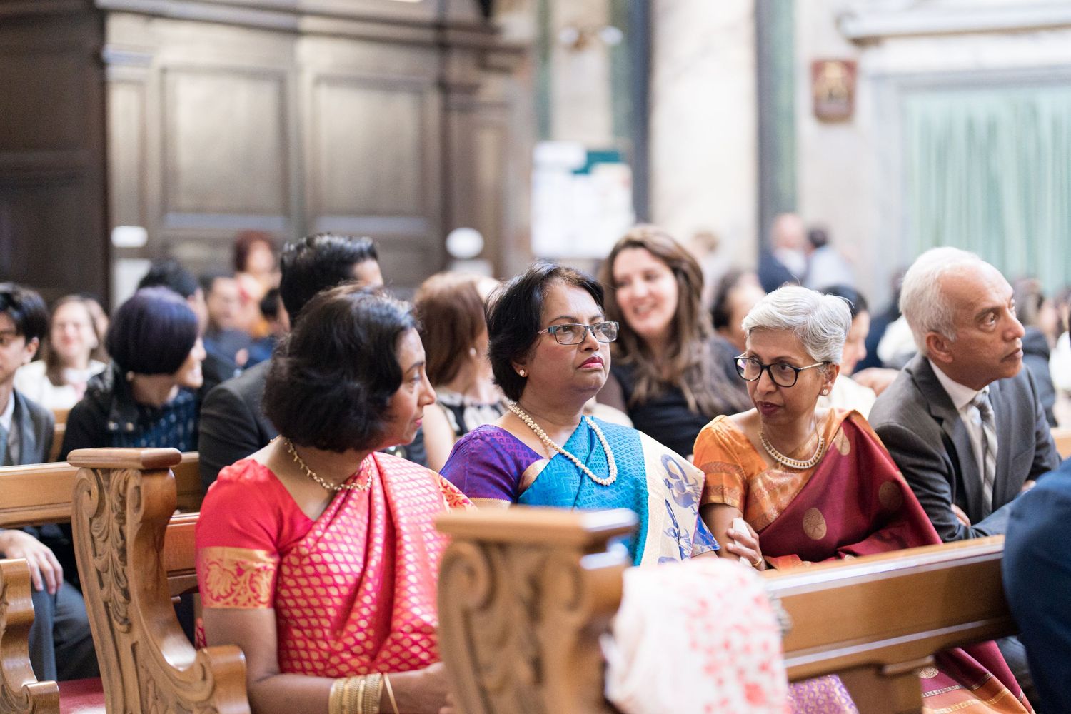 Church congregation seated in wooden pews during formal ceremony.