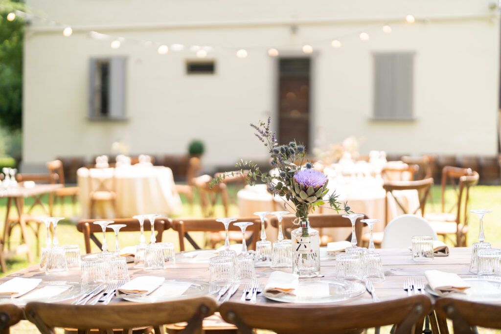 Elegant wedding reception tables set with white linens and string lights in an outdoor venue.