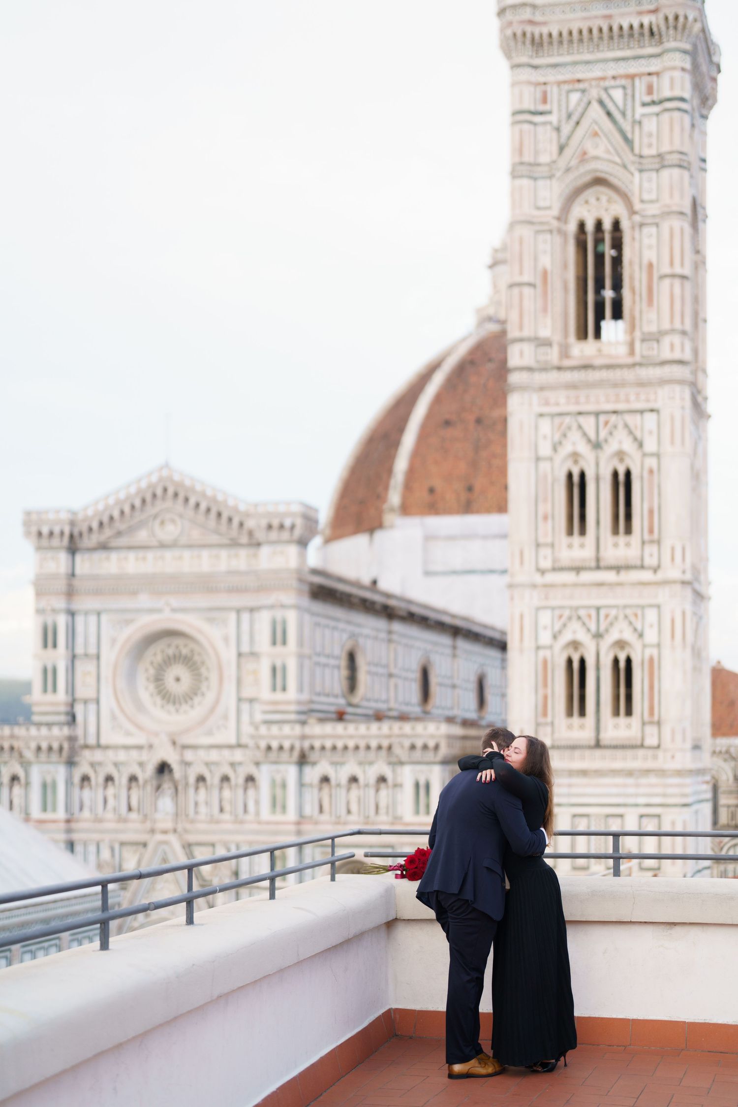 A couple admires the view of Florence Cathedral and Giotto's Bell Tower from a terrace in Italy.