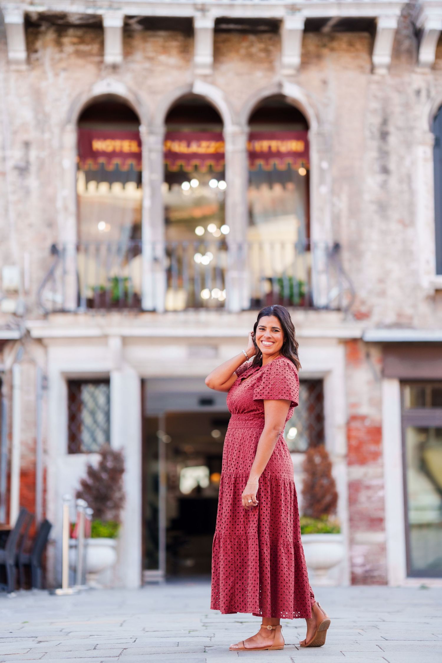 Woman in red polka dot dress smiling in front of Hotel Palazzo Vitturi in Venice, Italy.