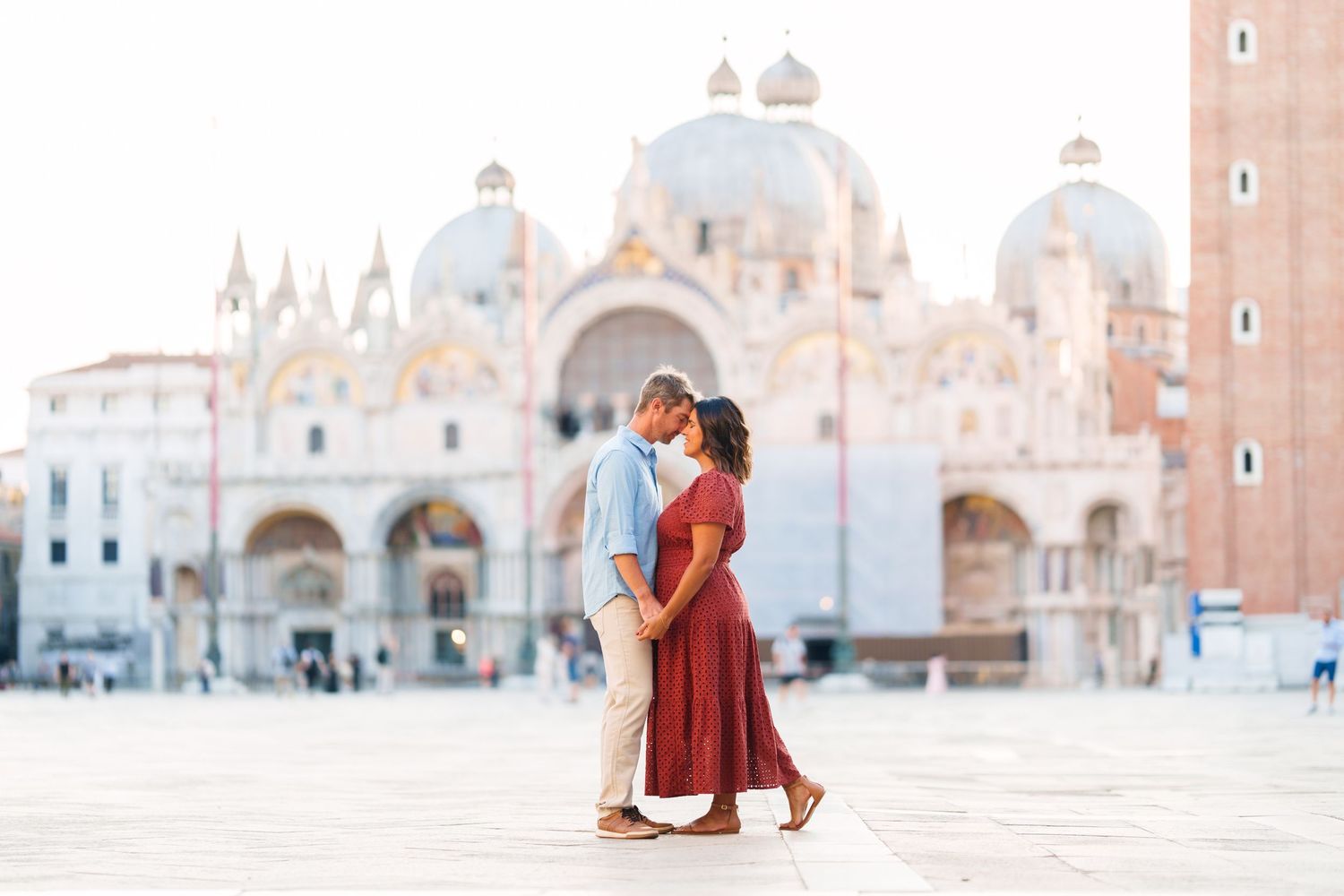 Couple sharing a romantic kiss in St. Mark's Square, Venice, with the iconic Basilica di San Marco in the background.