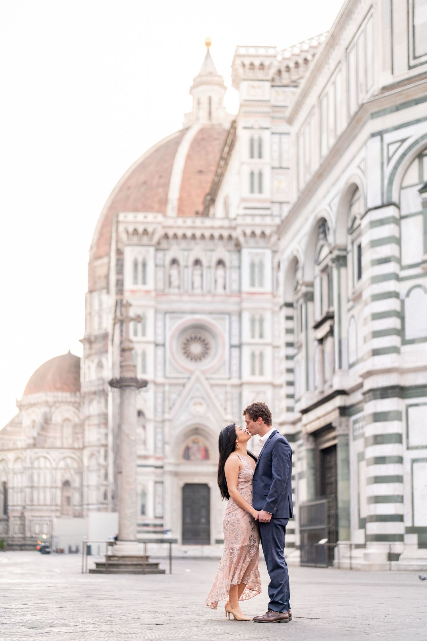 A couple embraces in front of the historic Florence Cathedral and Duomo in Italy during a romantic moment.