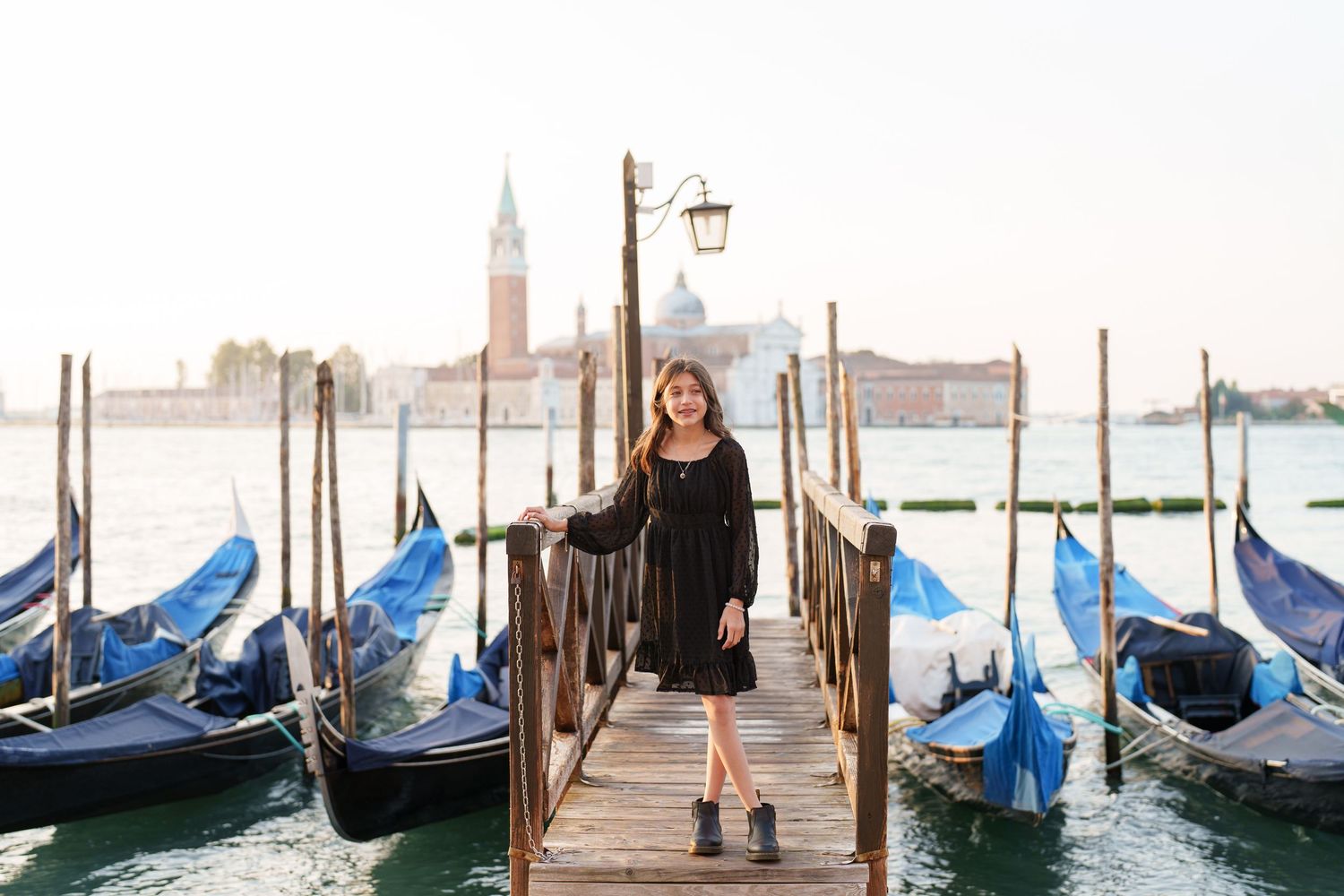 Gondolas sway gently at a wooden dock in Venice with the iconic San Giorgio Maggiore church visible in the background.