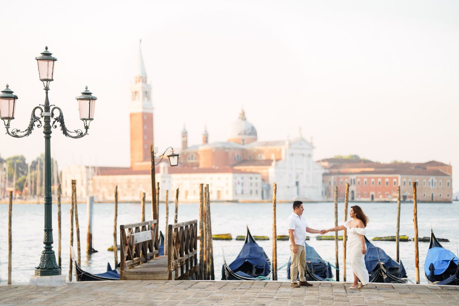 Ornate street lamps line the waterfront in Venice with the iconic San Giorgio Maggiore church visible in the background.